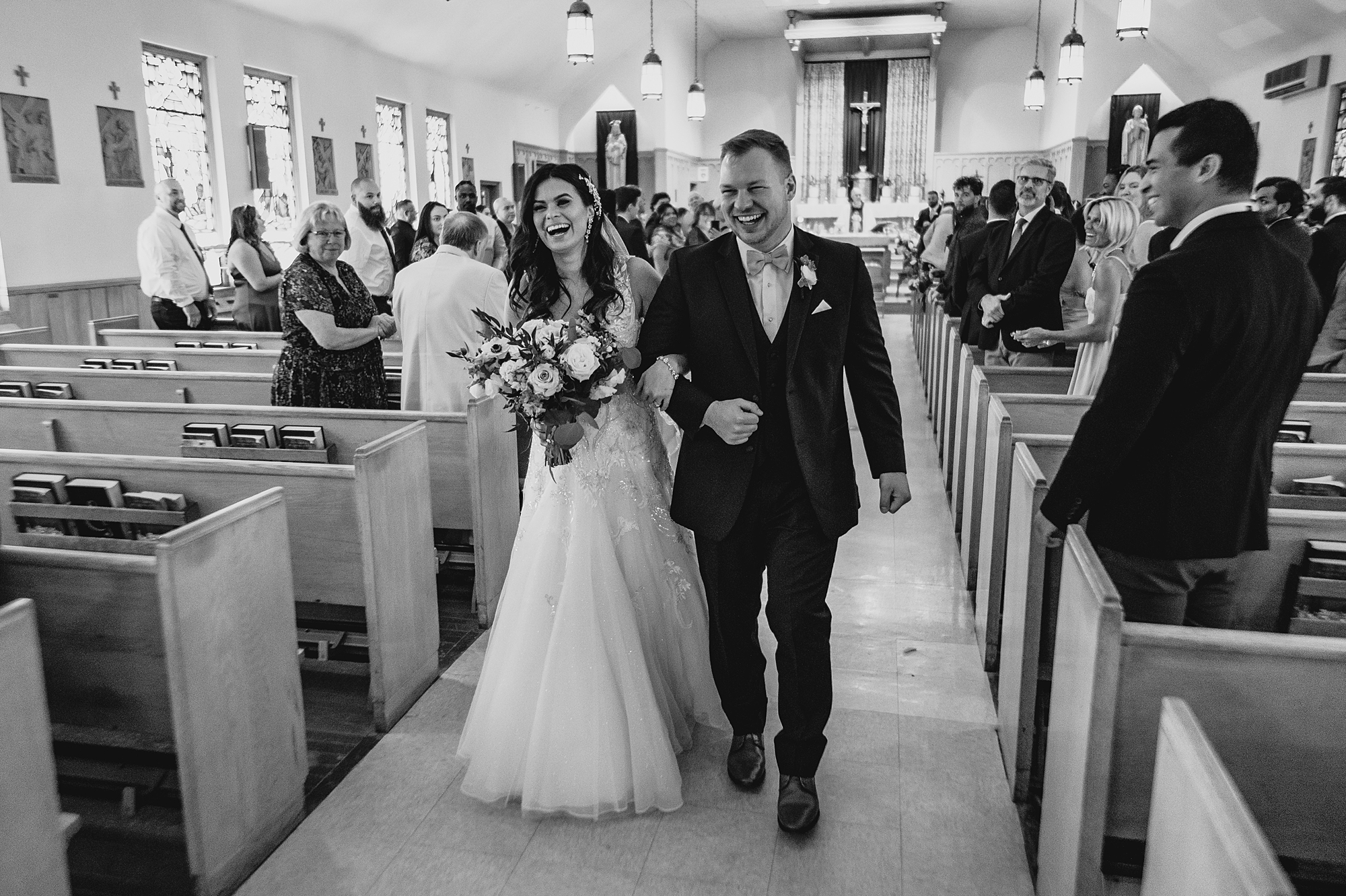 bride and groom smile walking up aisle after traditional church ceremony
