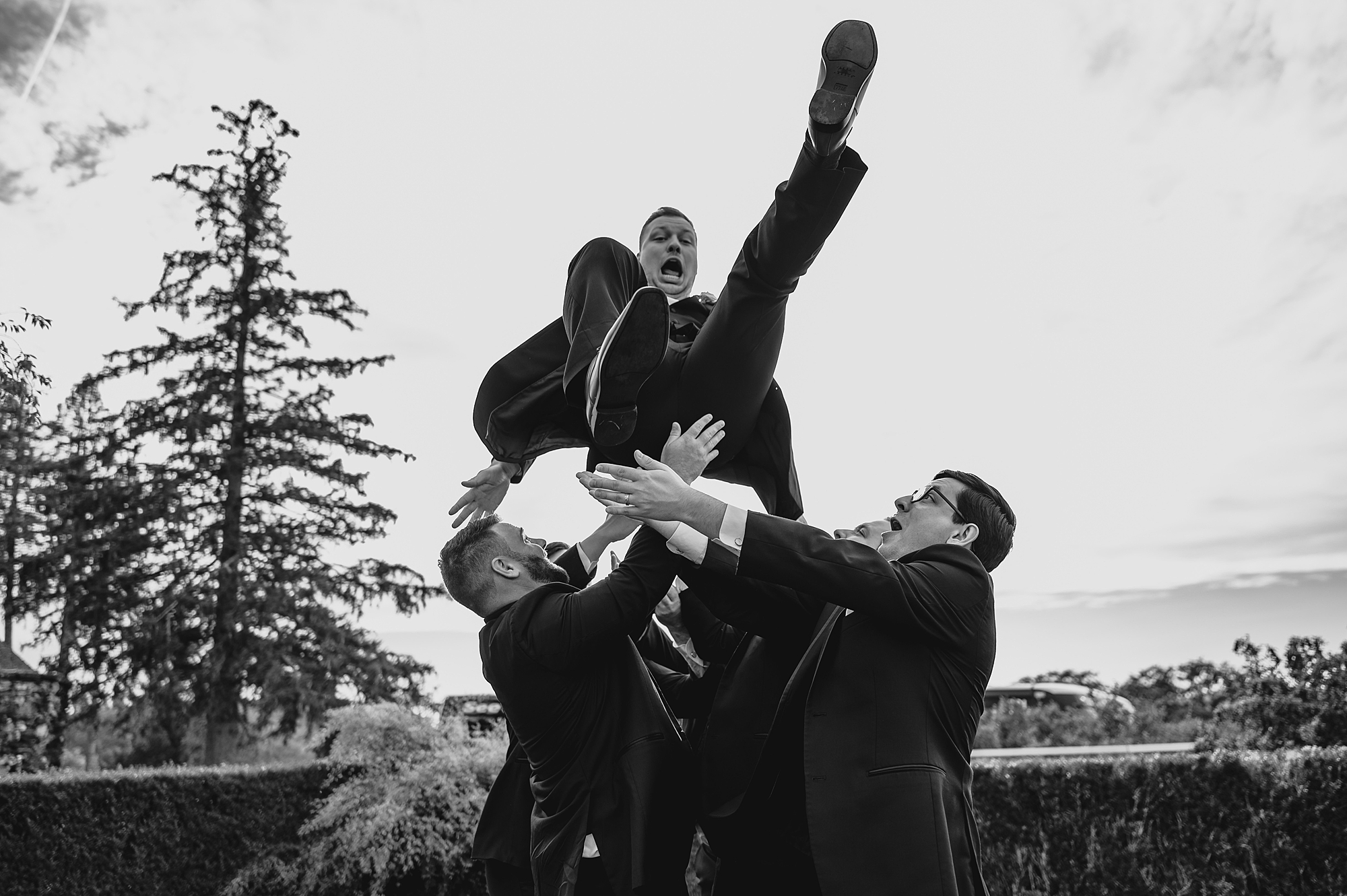 groomsmen throw groom in the air during photos at the Garrison
