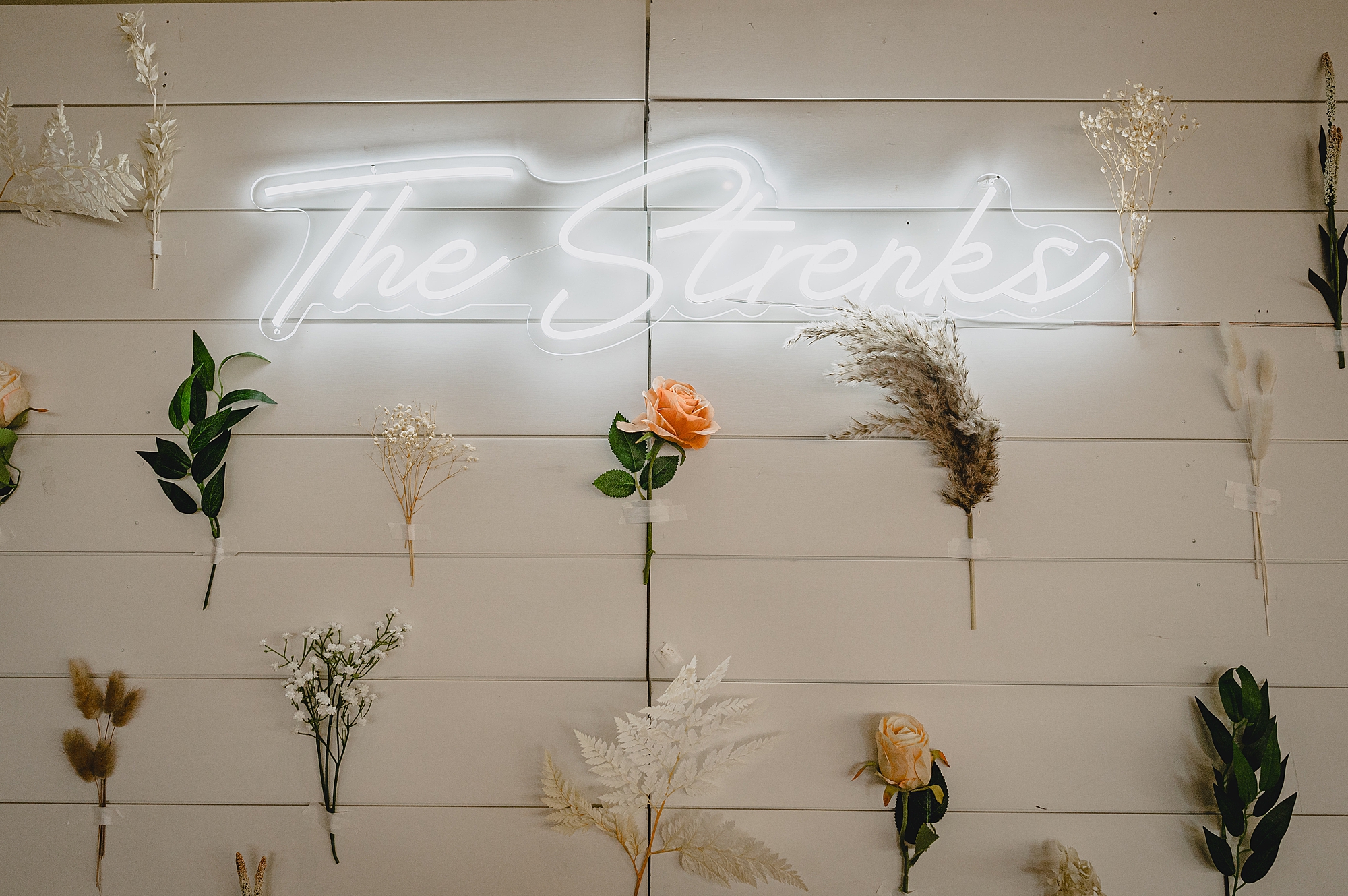 custom neon sign with hanging flowers on wall at reception