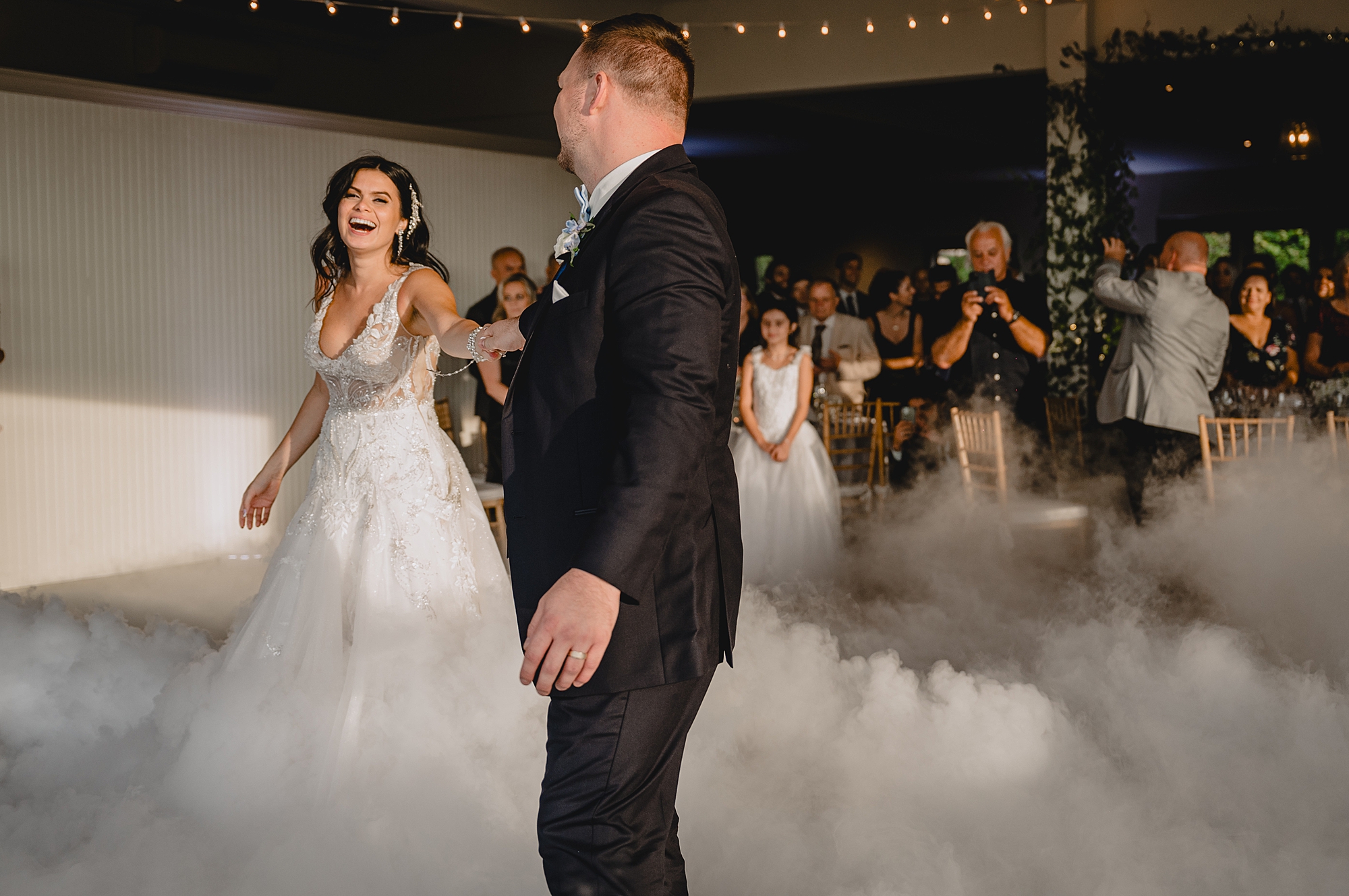 groom twirls bride on dance floor with fog around them at wedding reception at the Garrison