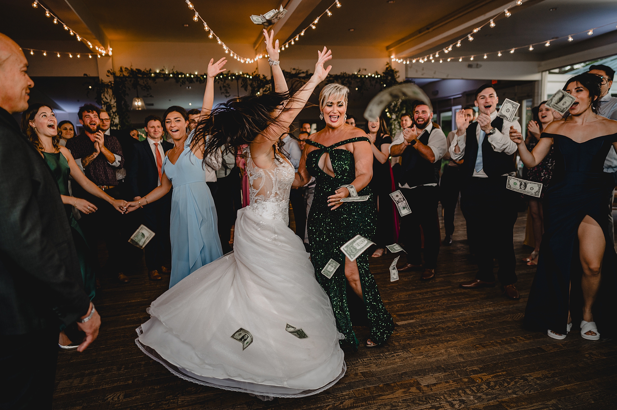 bride twirls around on dance floor with guests while money falls around them