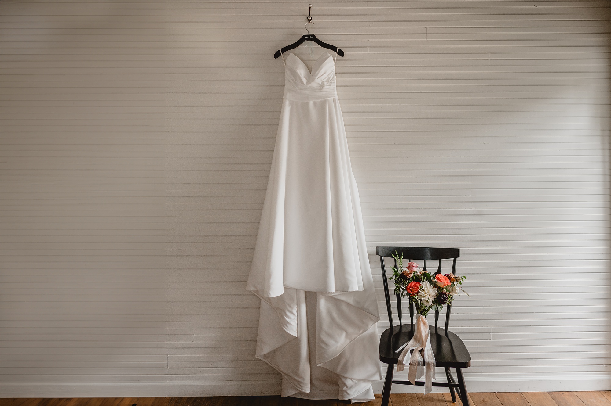 wedding dress hangs by wooden chair at Waterloo Village