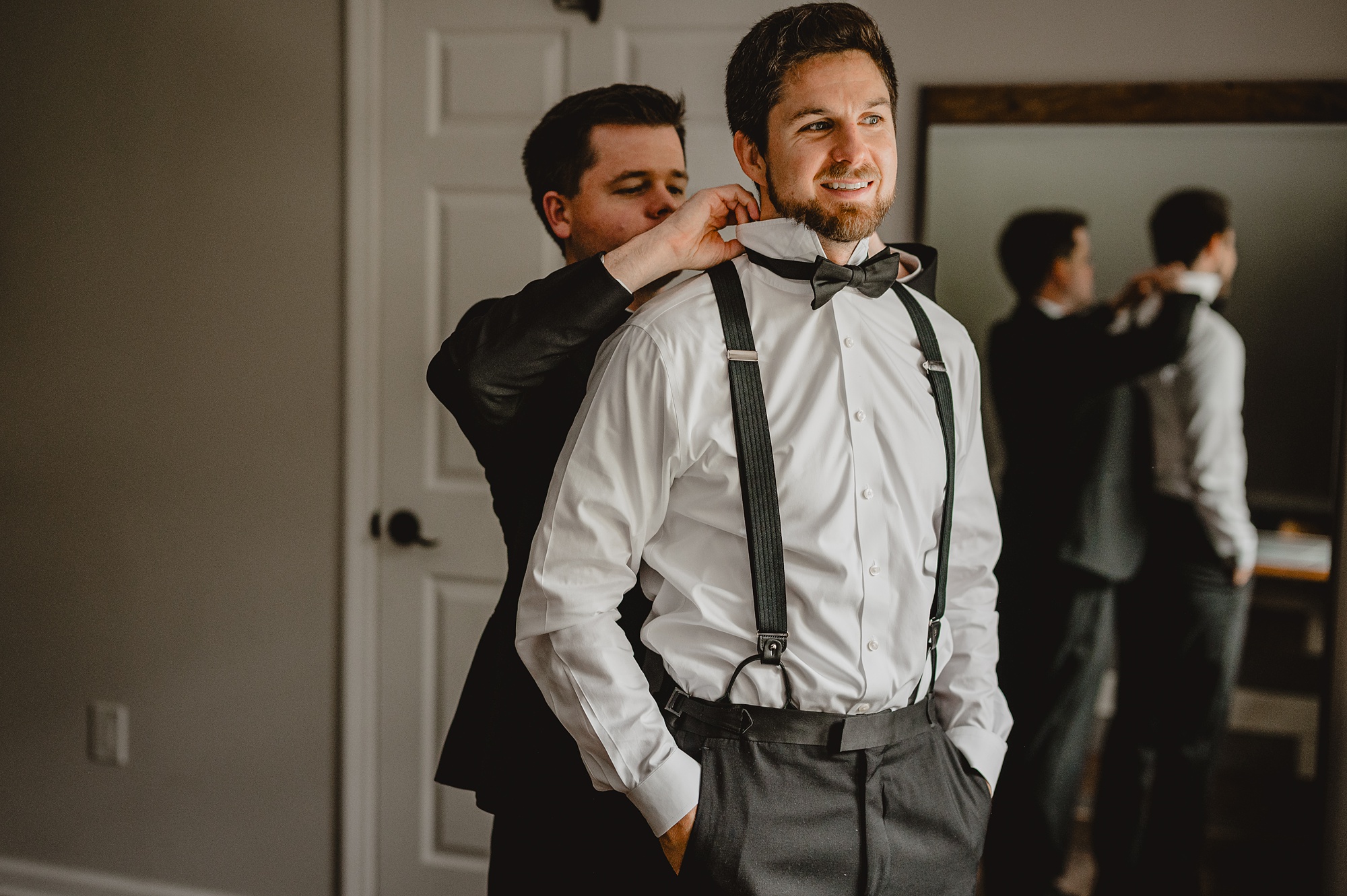 groomsman helps groom with bowtie during prep for NJ wedding