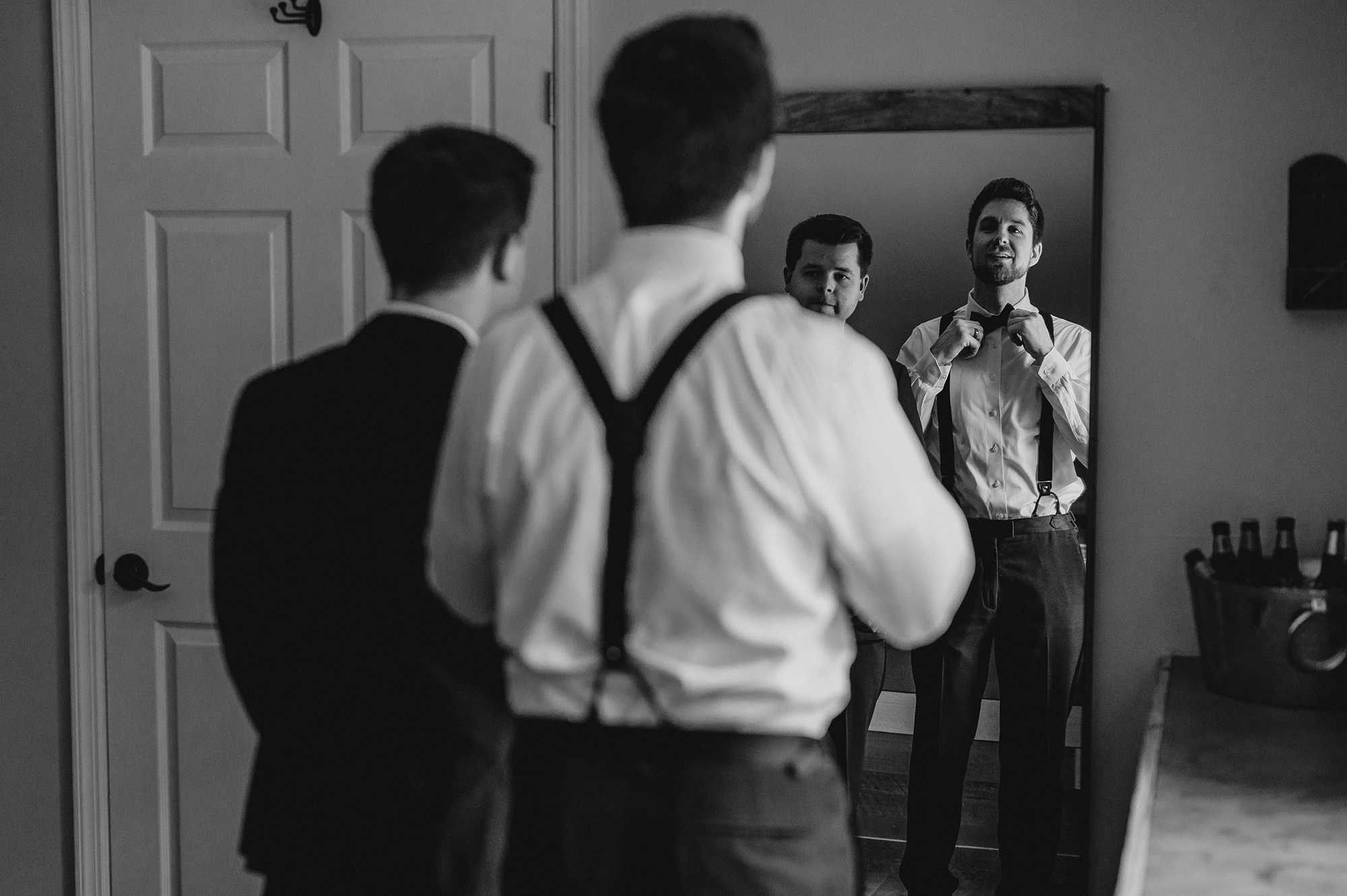 groom adjusts tie in mirror at Waterloo Village