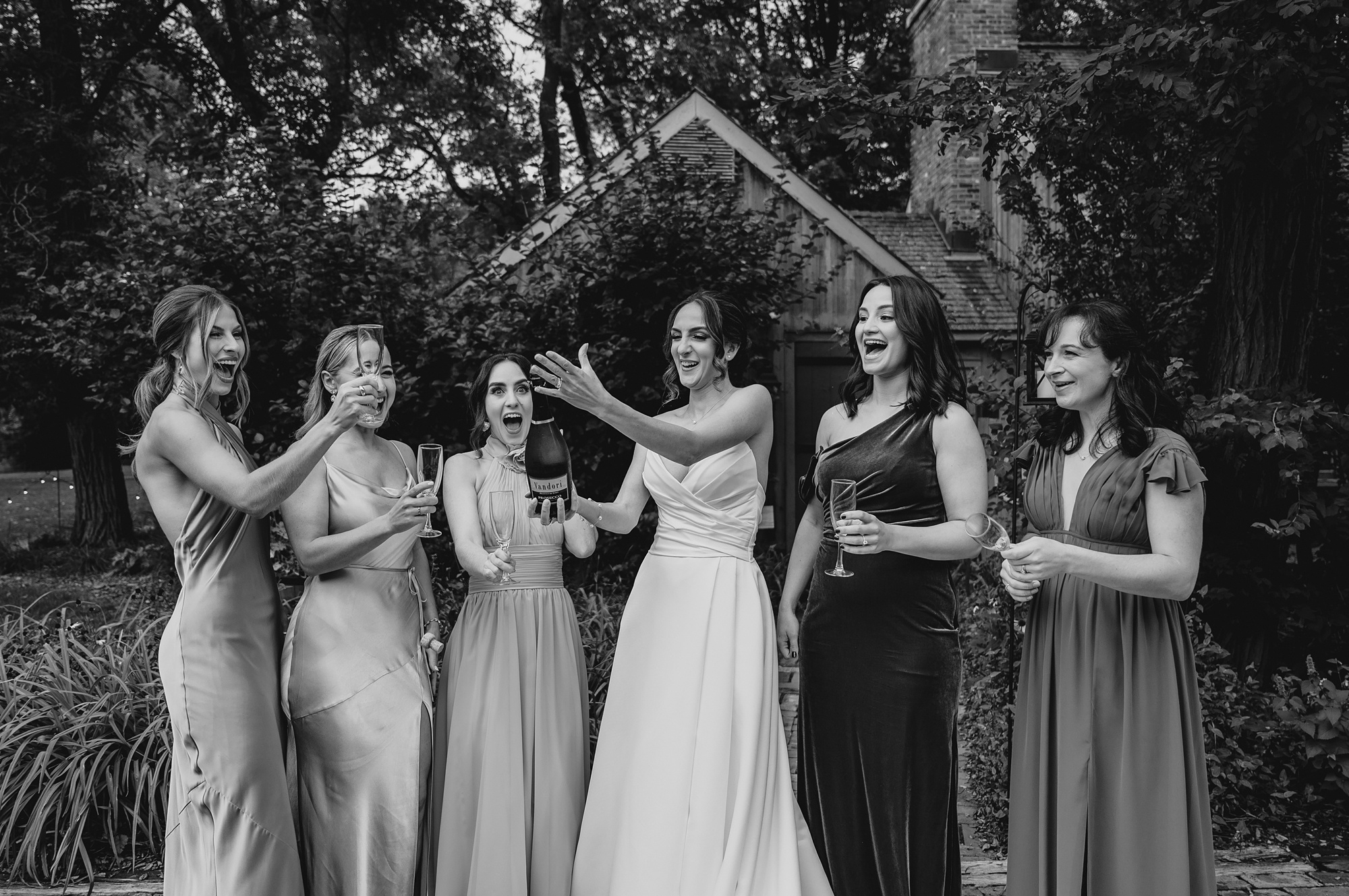 bride pops champagne with bridesmaids before fall wedding 