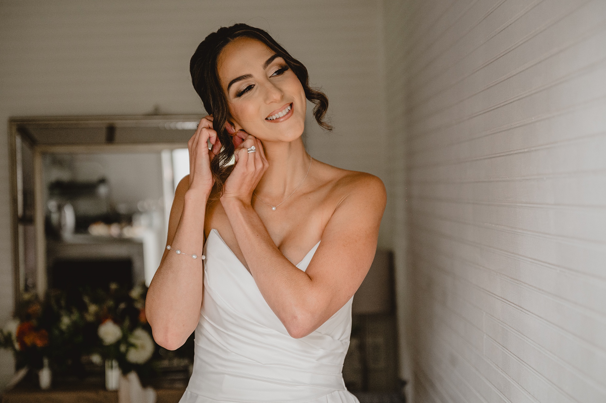 bride leans head adjusting earring during prep for NJ wedding 