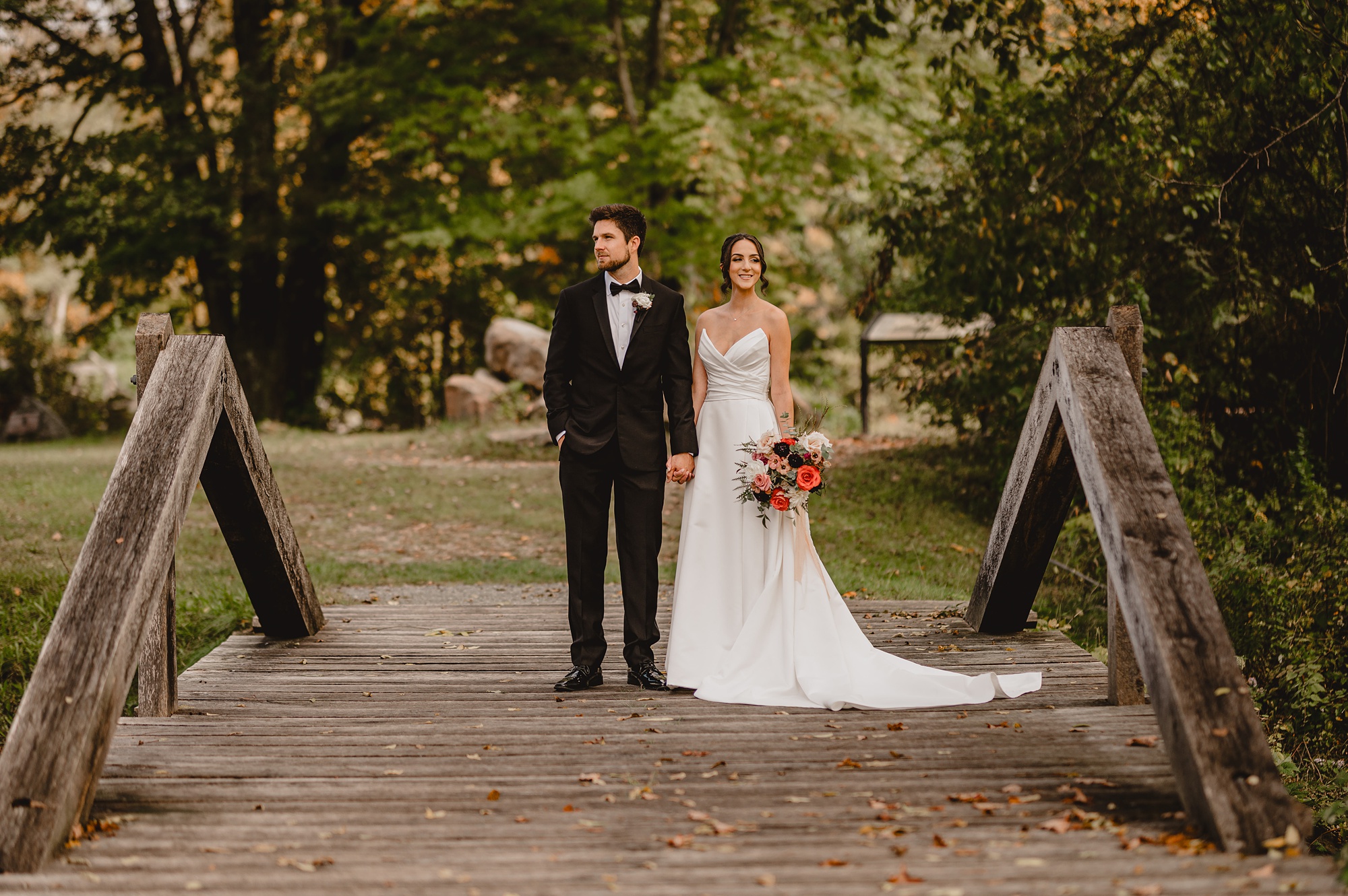 bride and groom hold hands on wooden bridge at Waterloo Village
