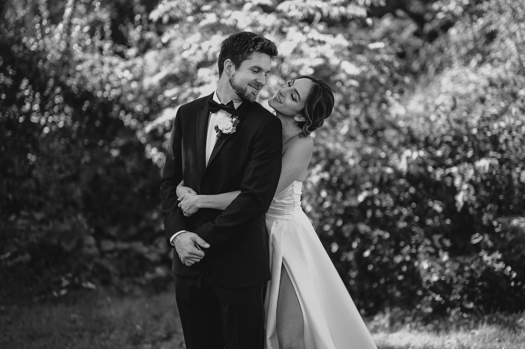 bride hugs groom from behind smiling up at him