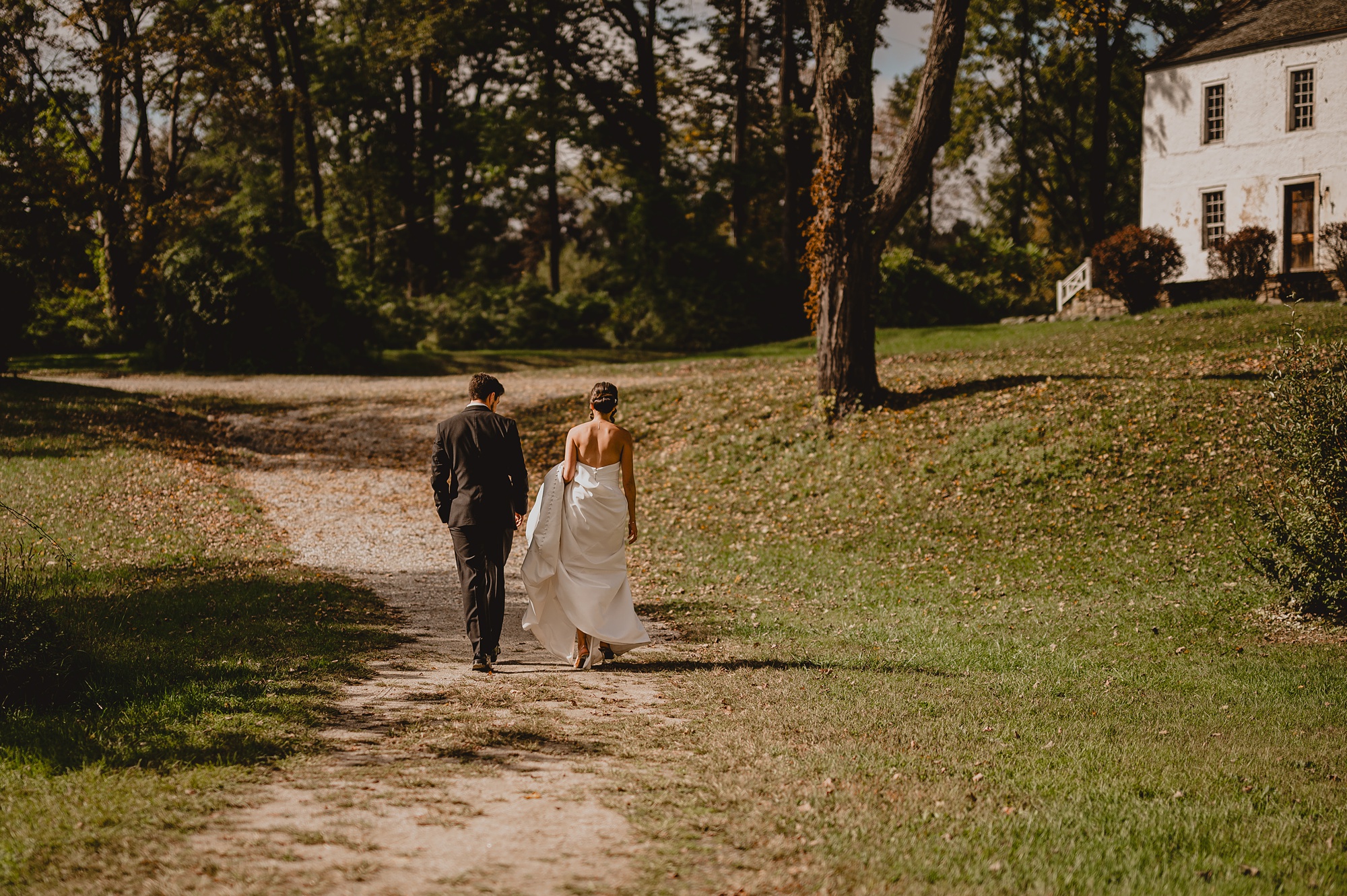 bride and groom walk up hill towards house at Waterloo Village