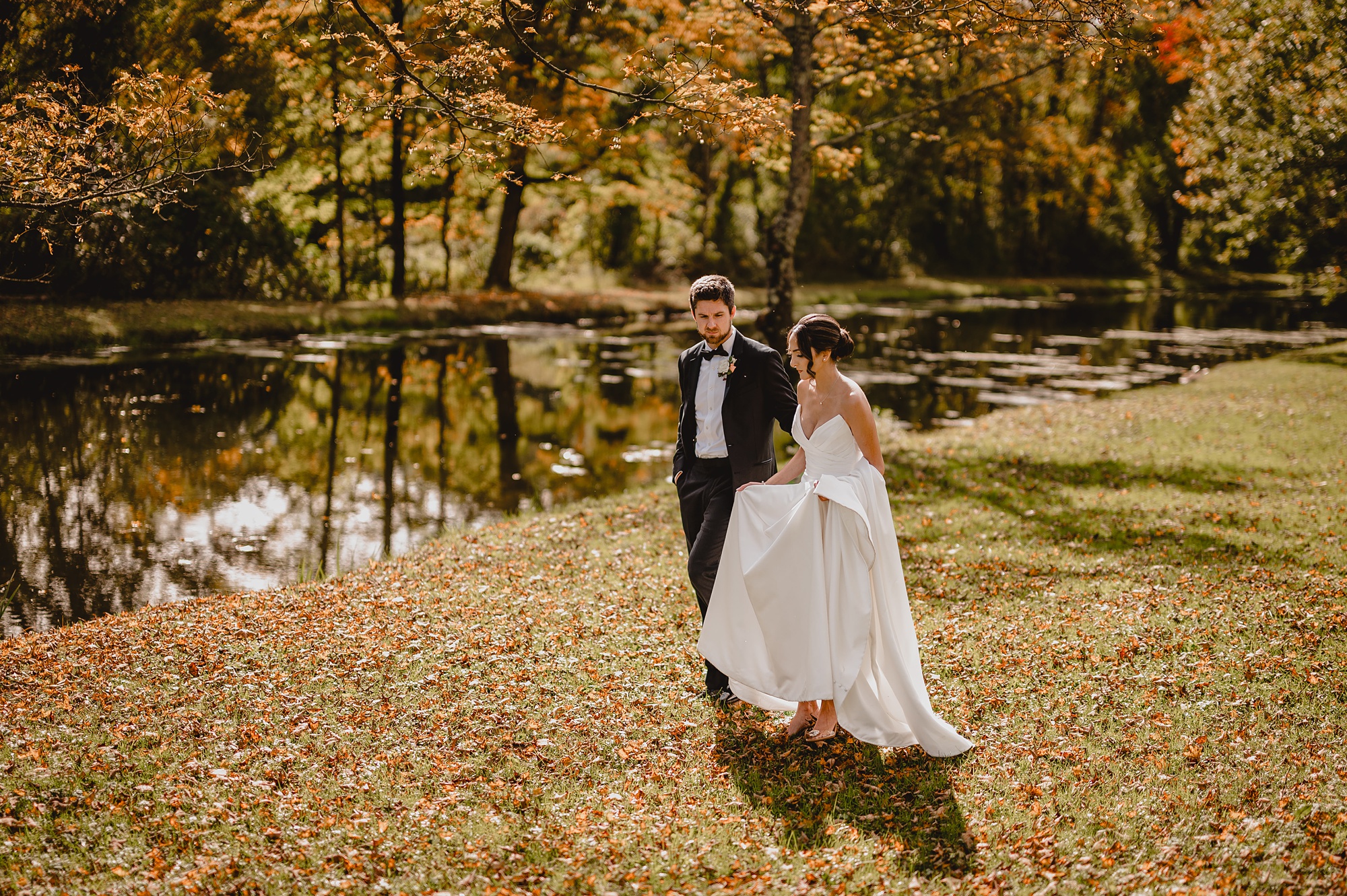 groom leads bride around pond at Waterloo Village