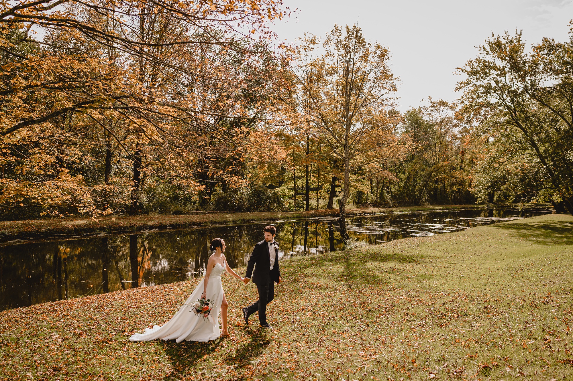 groom leads bride across lawn at Waterloo Village