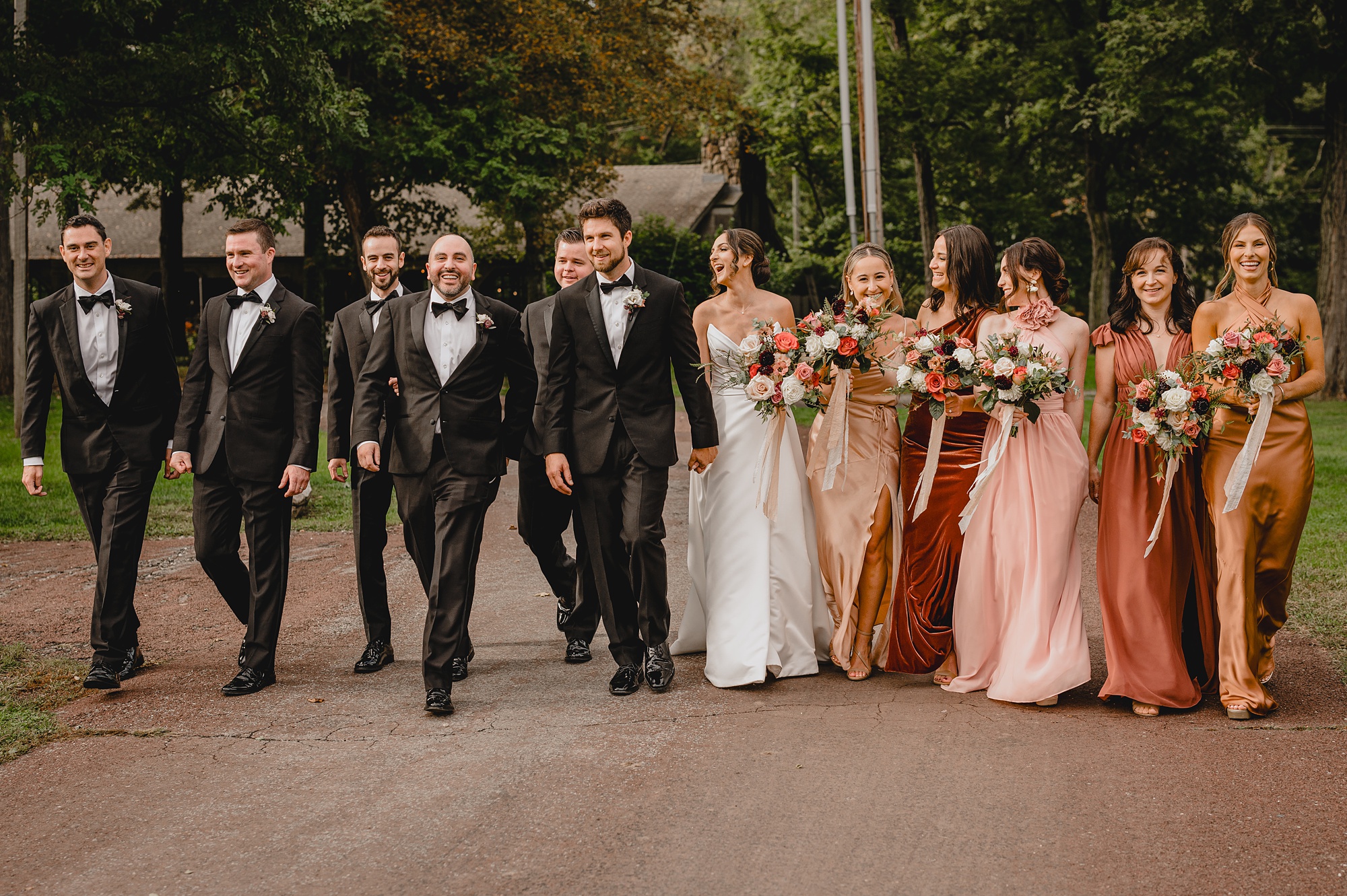 bride and groom walk with wedding party in pink and black attire 