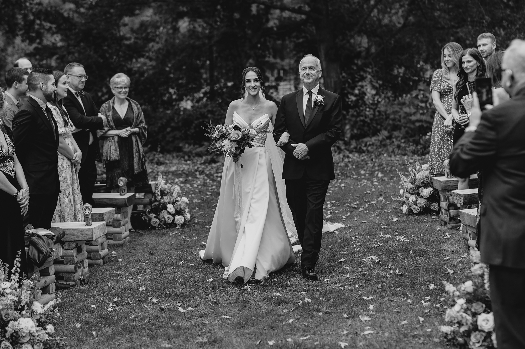 bride and father walk down aisle lined with flowers 