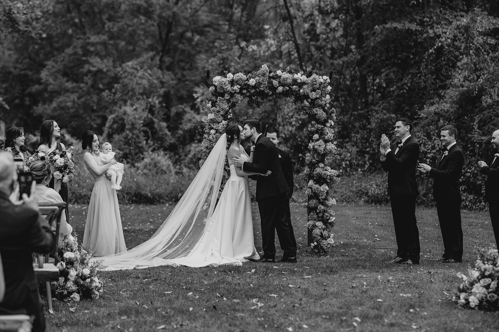 bride and groom kiss during wedding ceremony on lawn at Waterloo Village