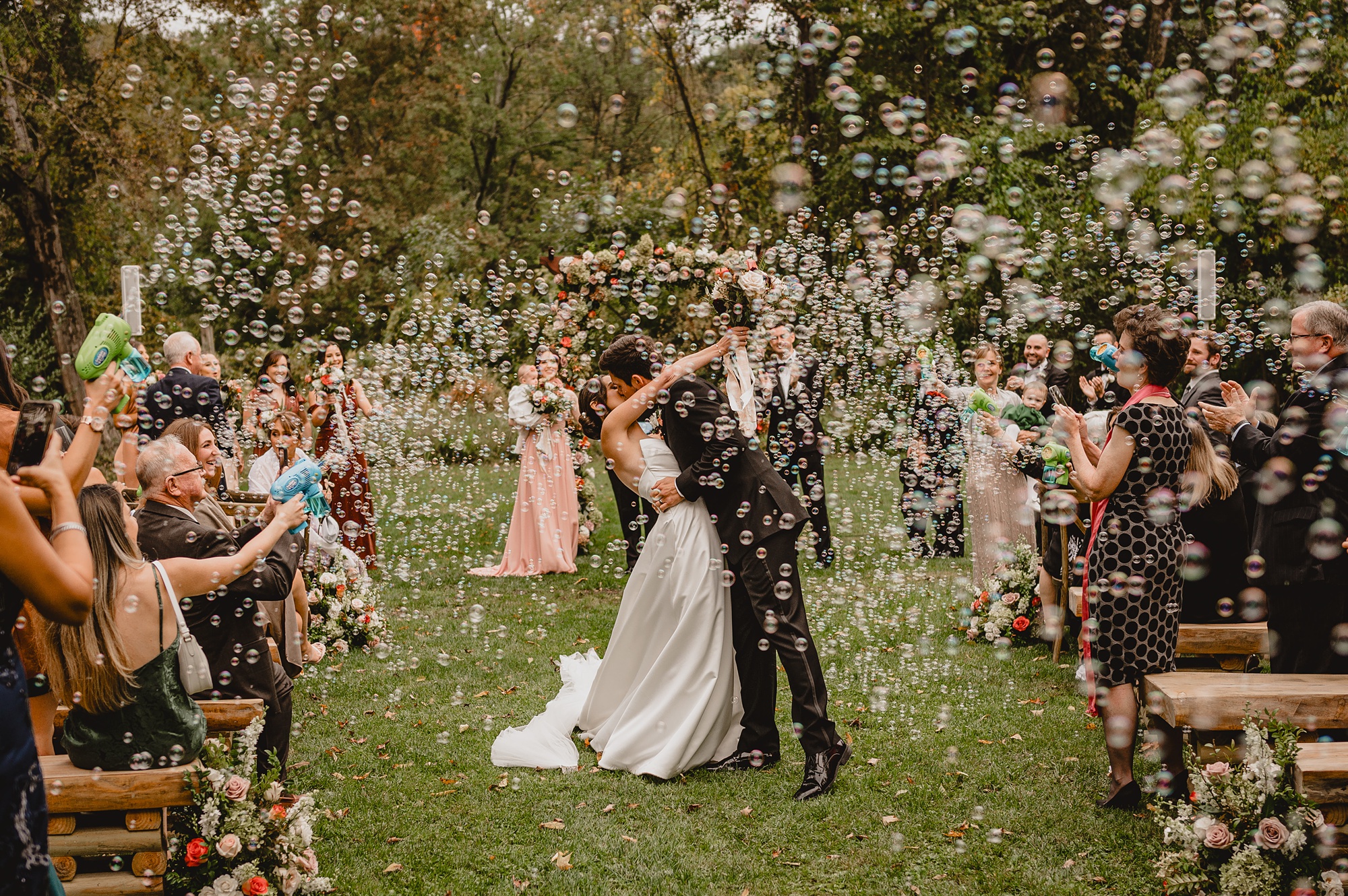 newlyweds kiss with bubbles floating around them in aisle at Waterloo Village