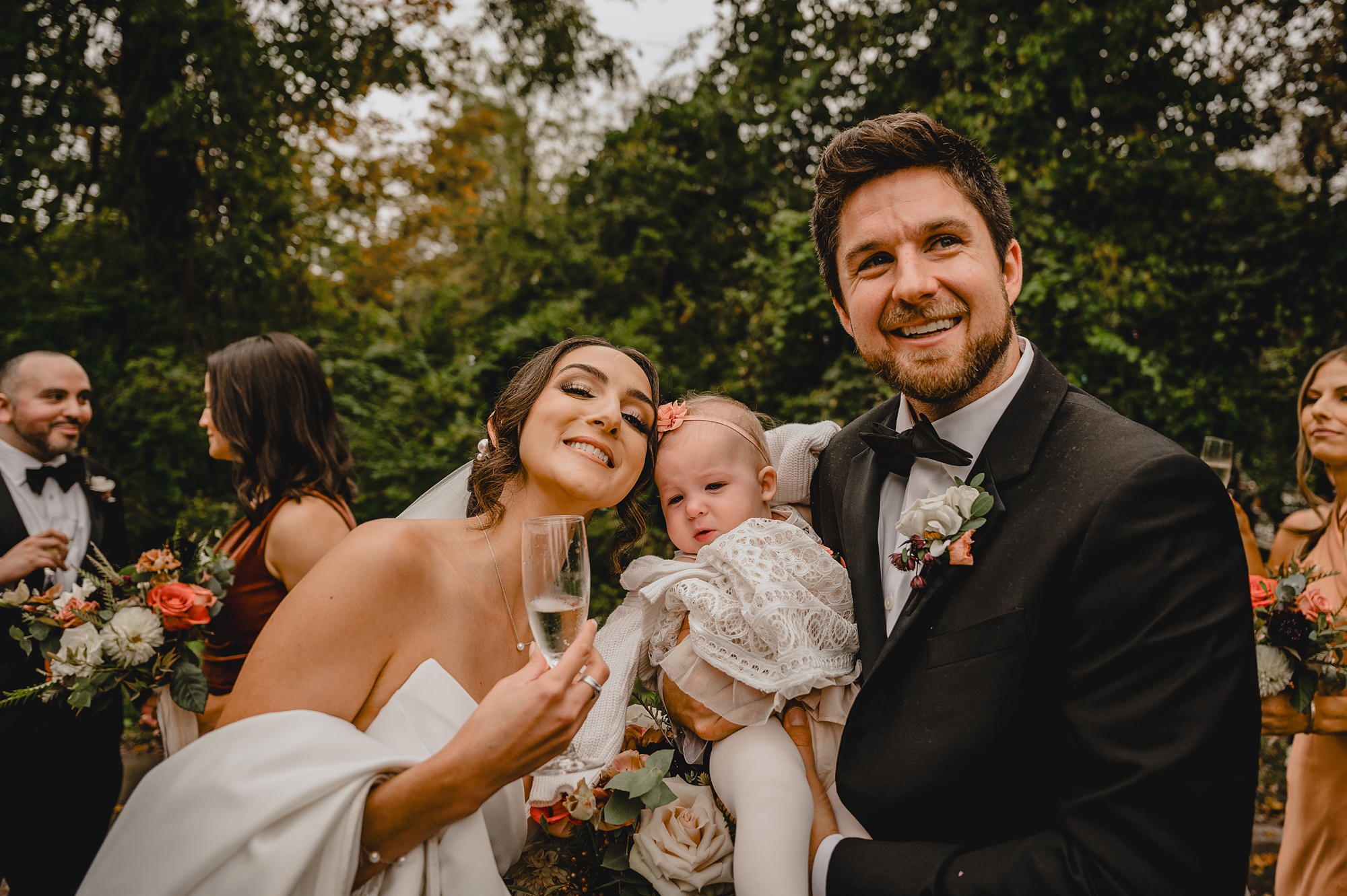 newlyweds hug toddler daughter on wedding day