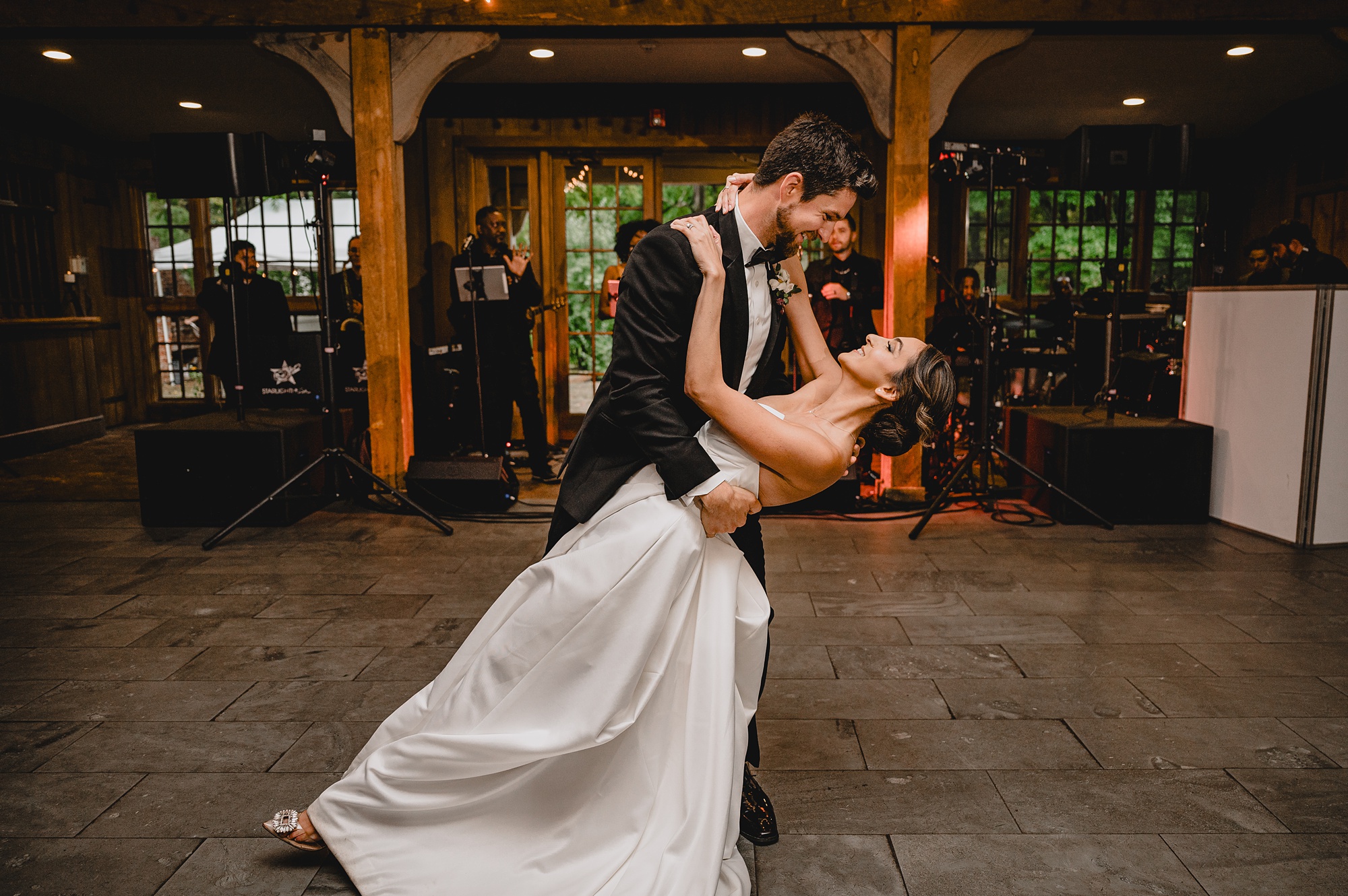 groom dips bride on dance floor in New Jersey barn