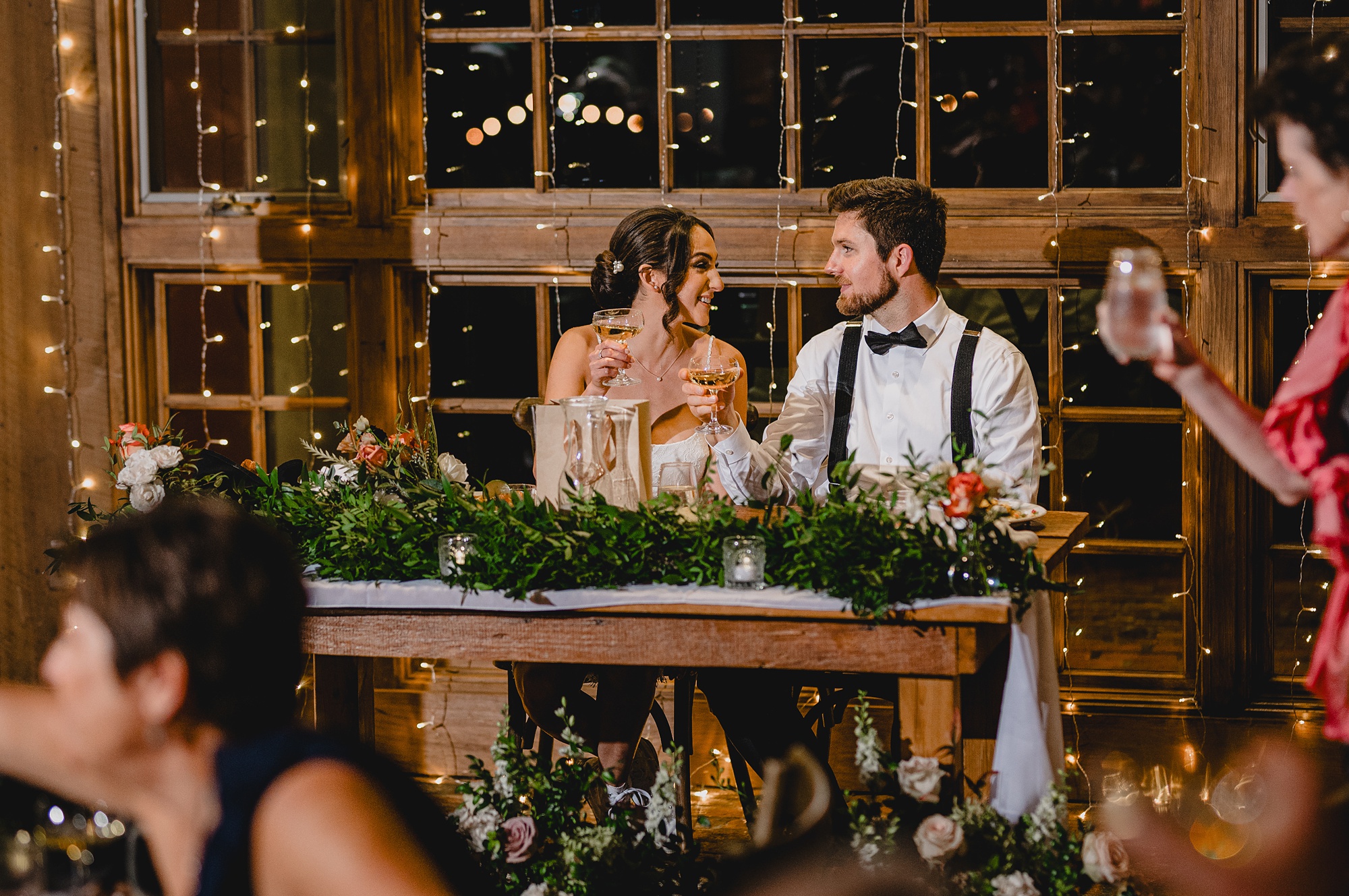 bride an groom smile at each other sitting at sweetheart table 