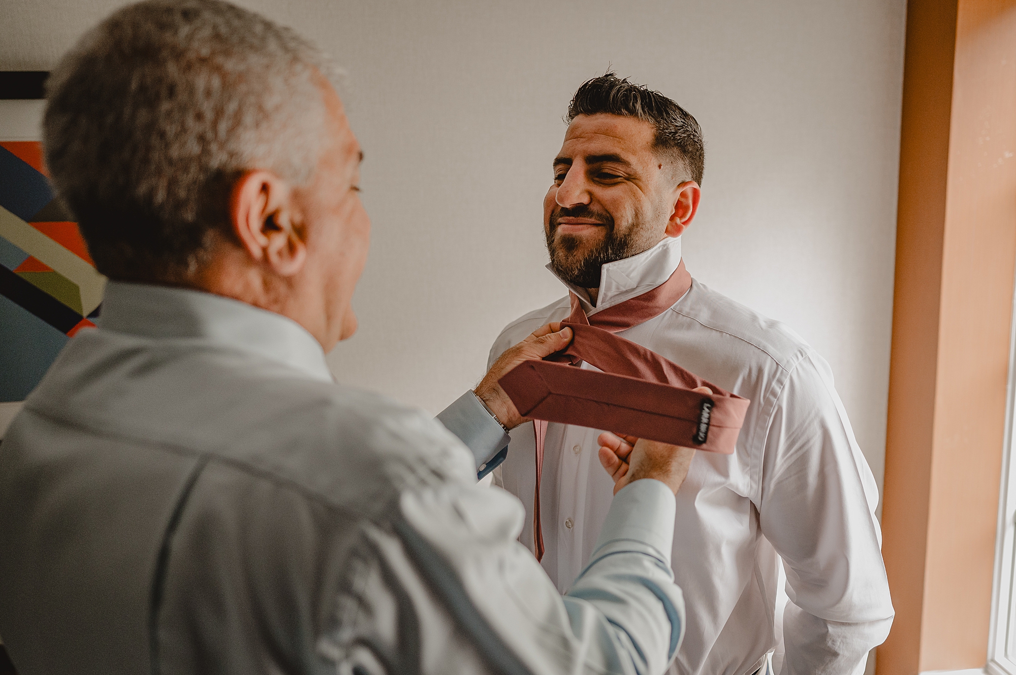 groom's father adjusts orange tie for groom