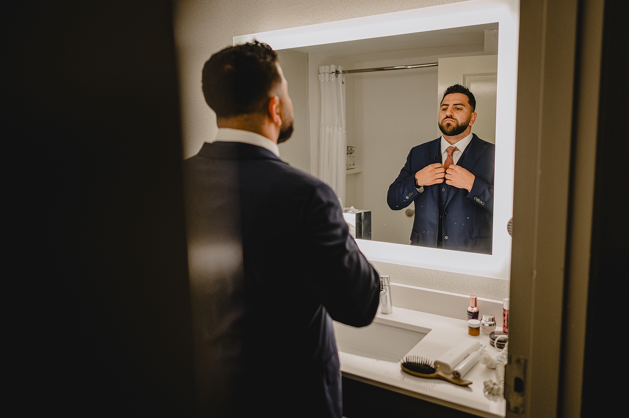 groom adjusts burnt orange tie in mirror at Skyview Golf Club