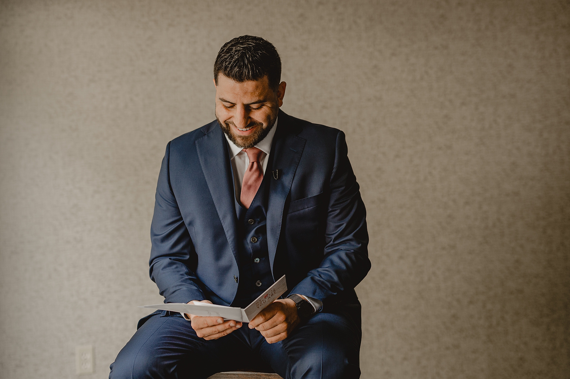 groom sits reading card on morning of wedding in suite at Skyview Golf Club