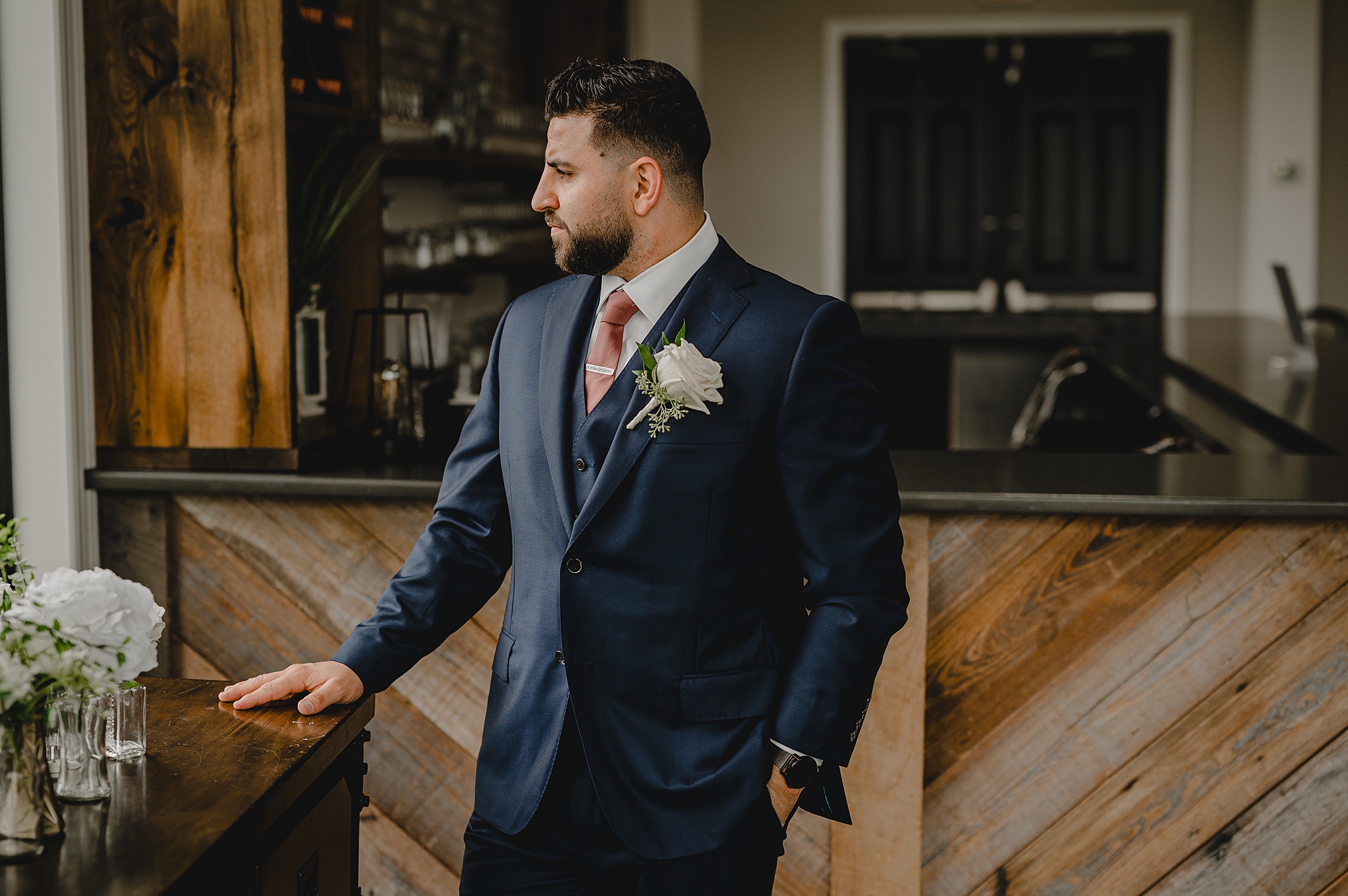 groom in navy suit looks out on patio at Skyview Golf Club