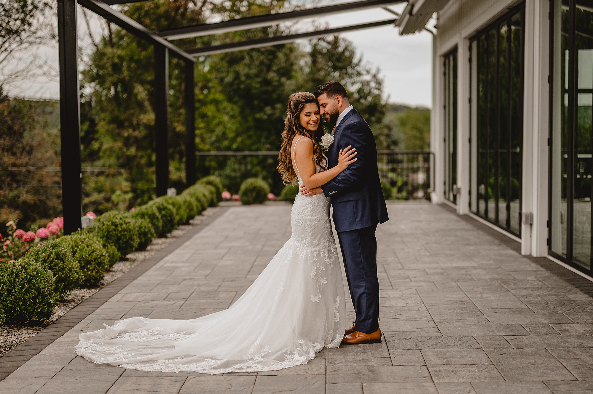 groom in navy suit hugs bride to him on brick patio at Skyview Golf Club