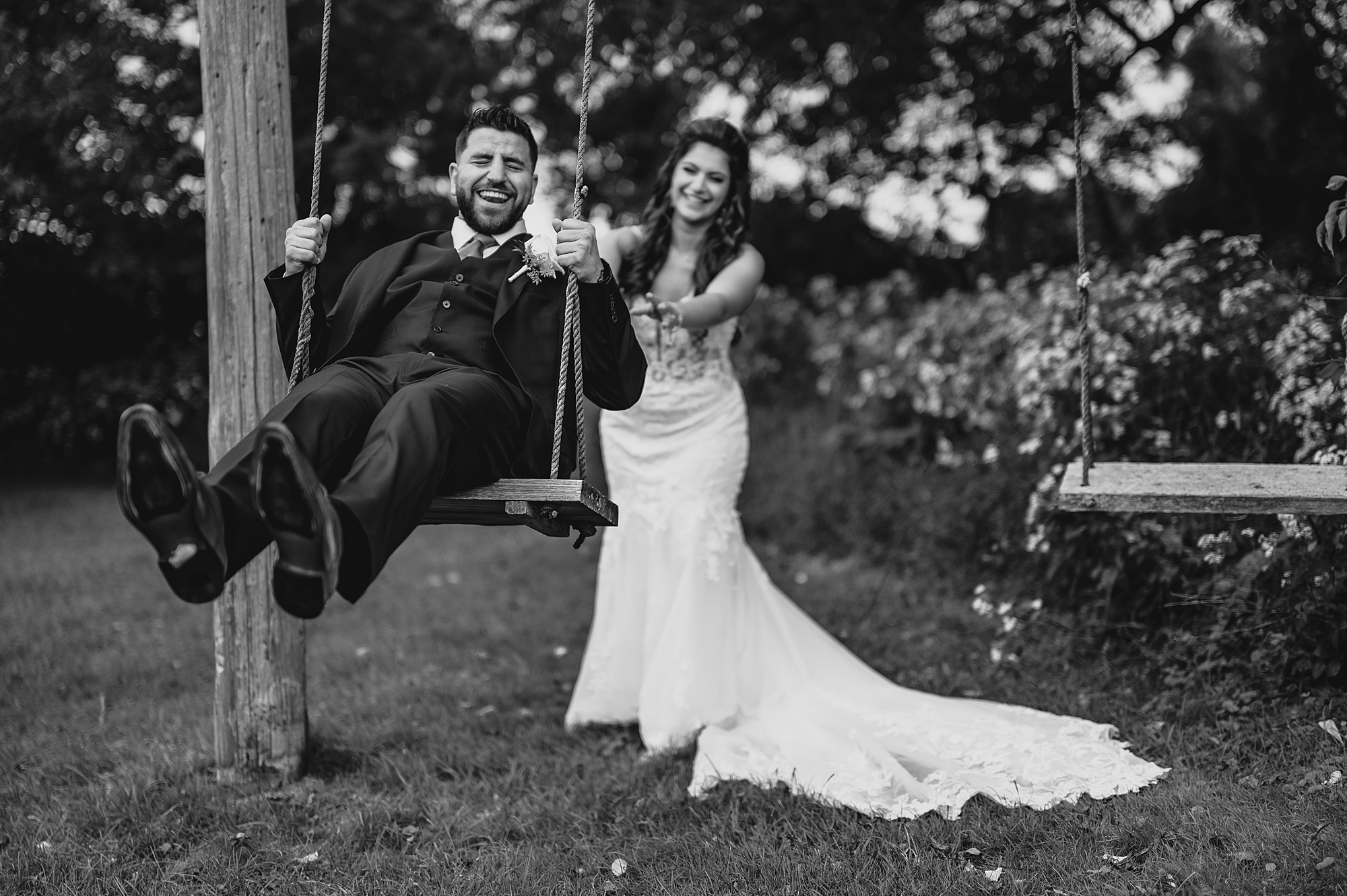 bride pushes groom on wooden swing at Skyview Golf Club
