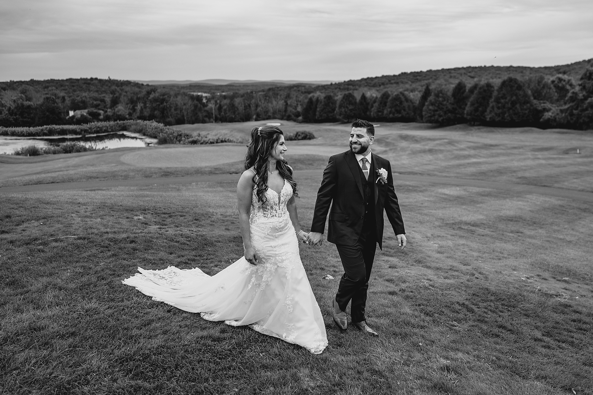 newlyweds hold hands walking down hill at Skyview Golf Club in New Jersey