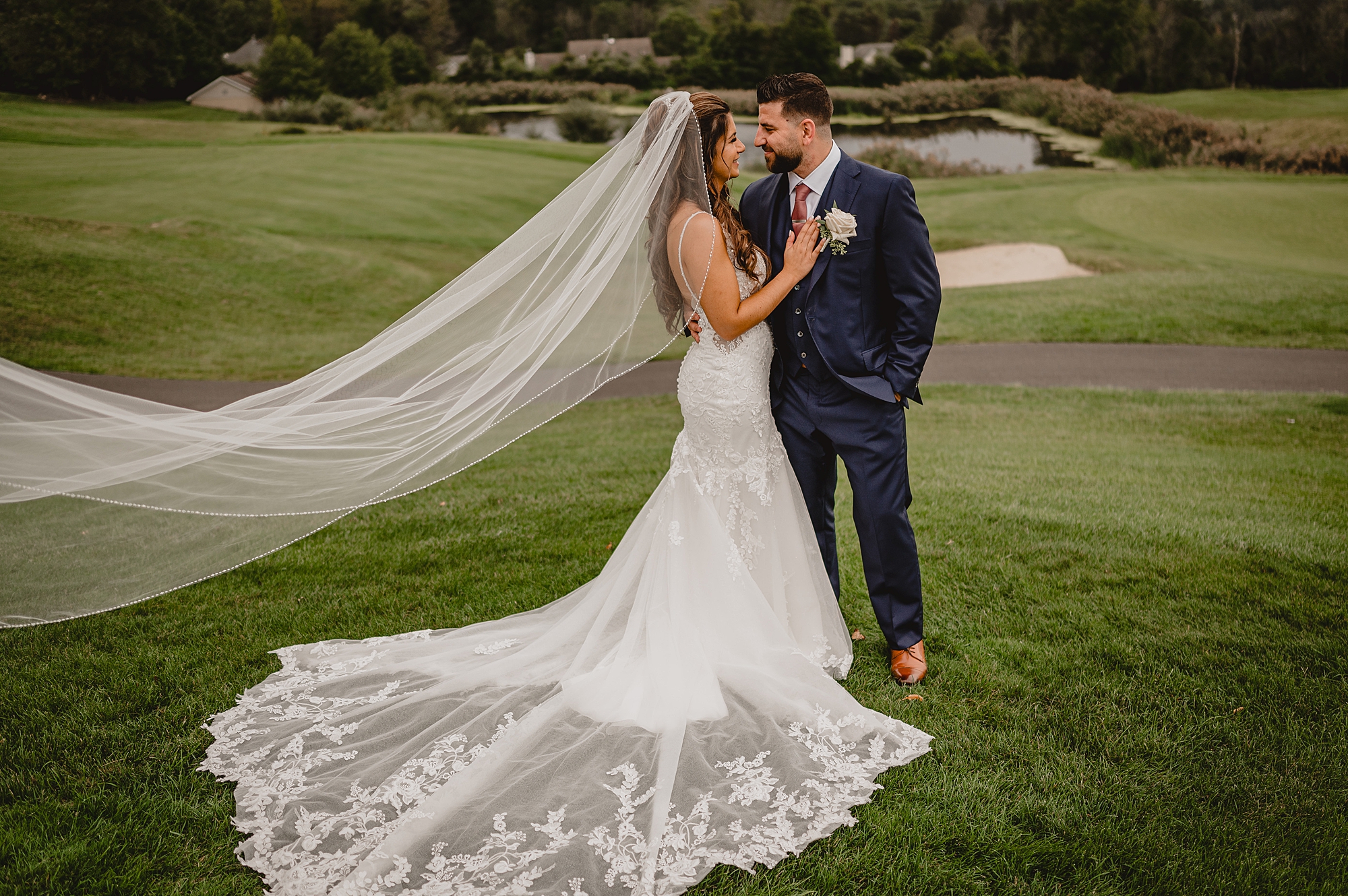newlyweds stand on golf course green hugging at Skyview Golf Club