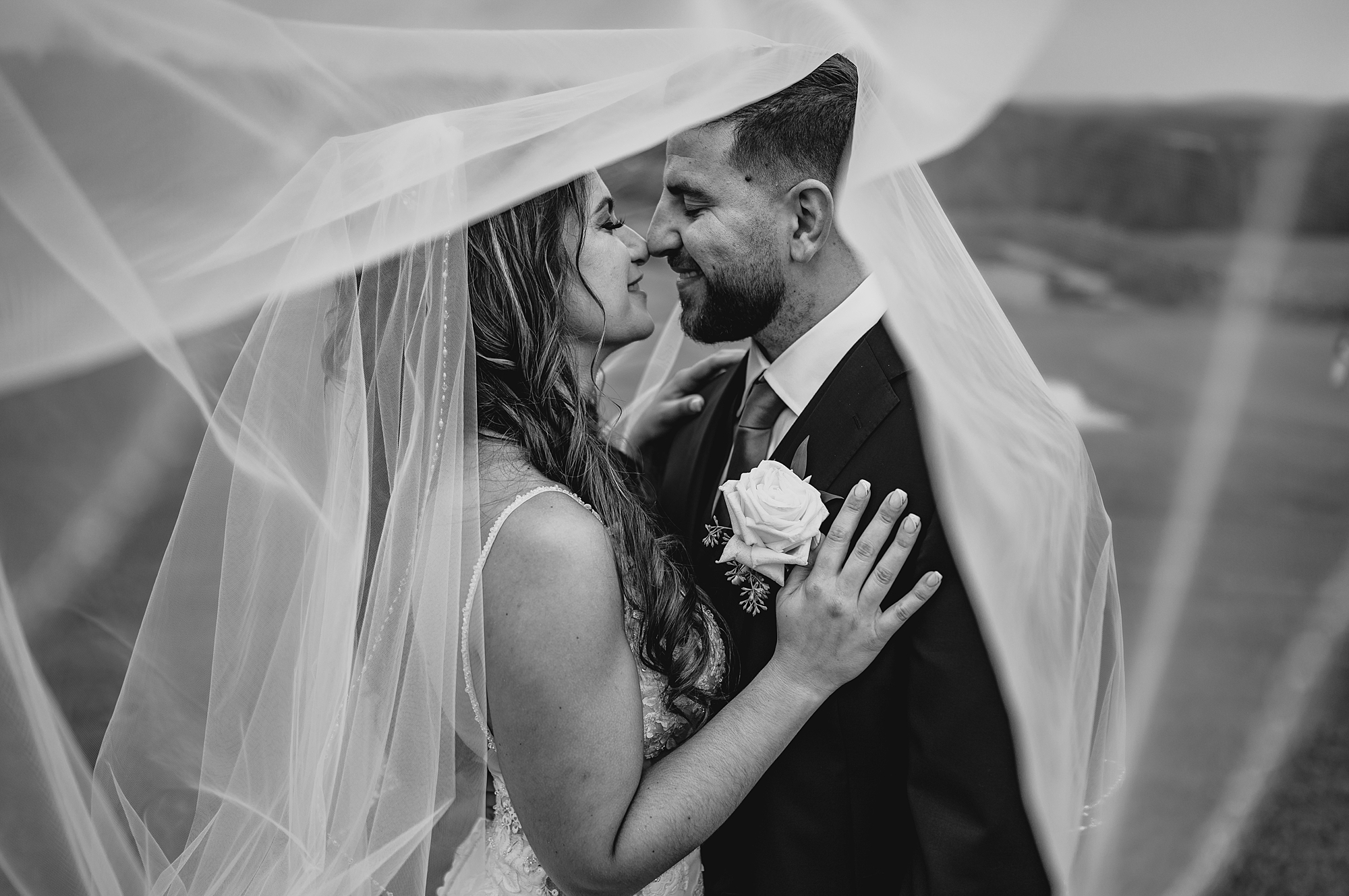 bride and groom lean together under veil on wedding day
