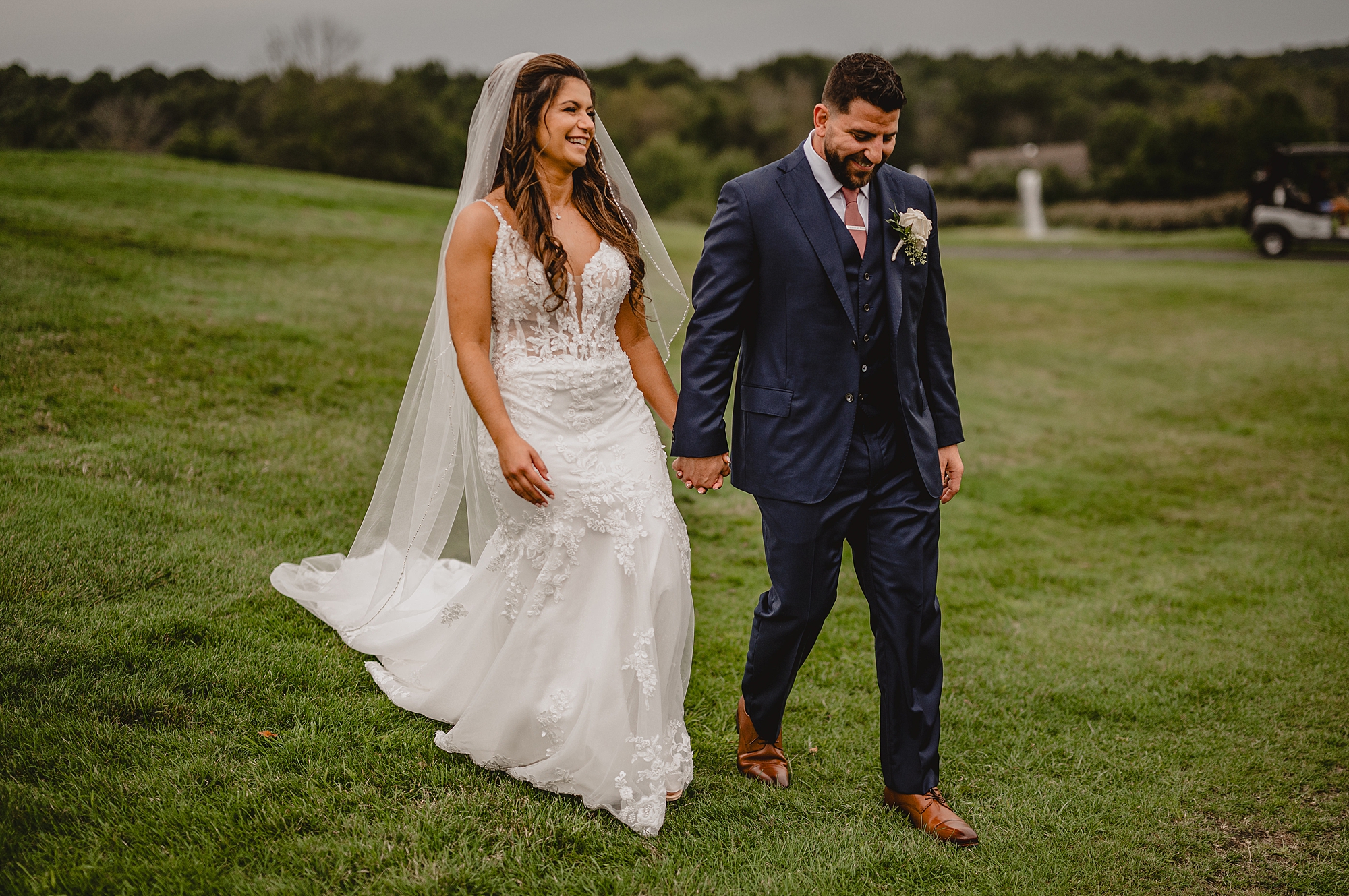groom in navy suit leads bride down hill at Skyview Golf Club