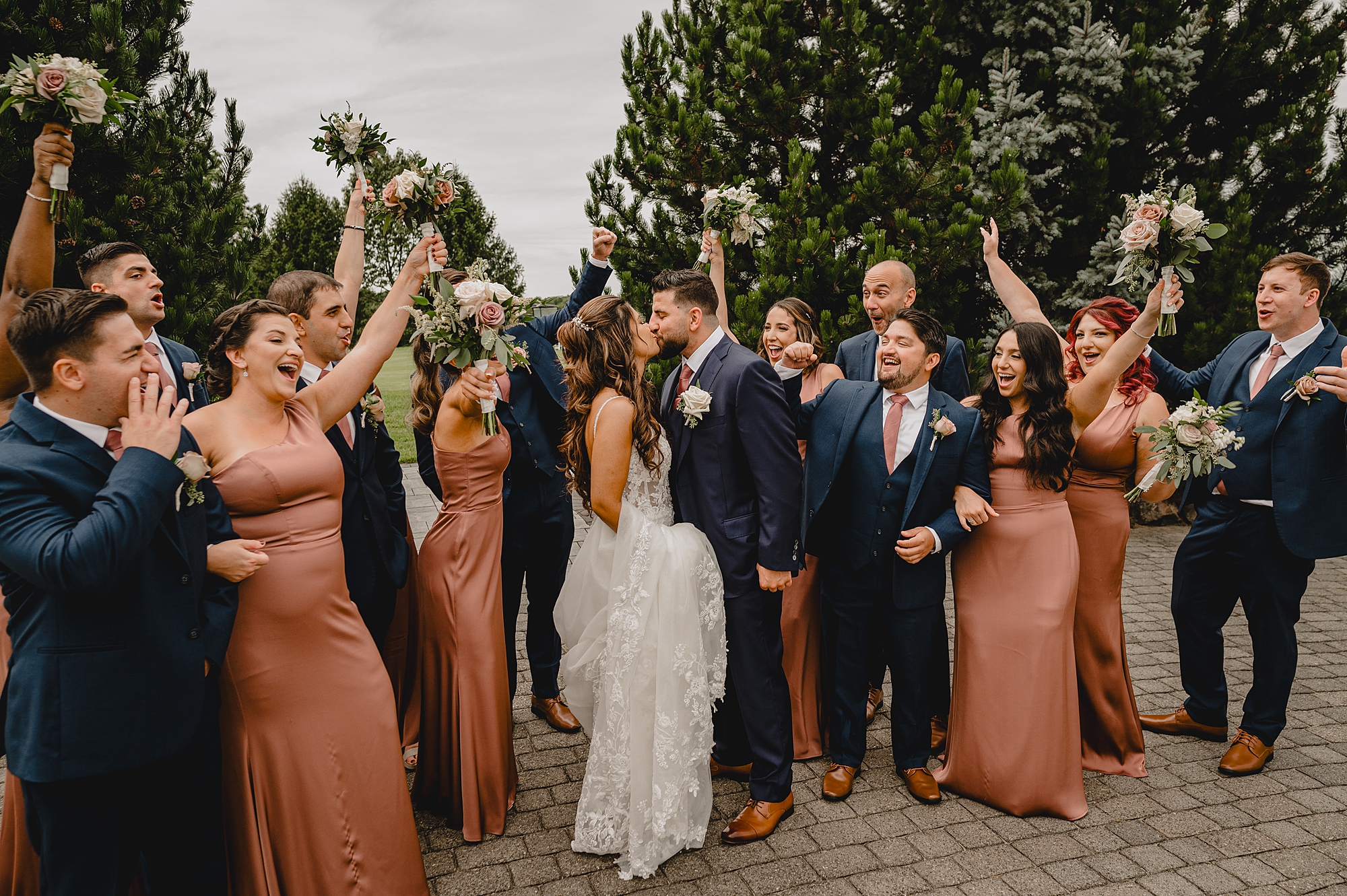 newlyweds kiss while wedding party cheers around them