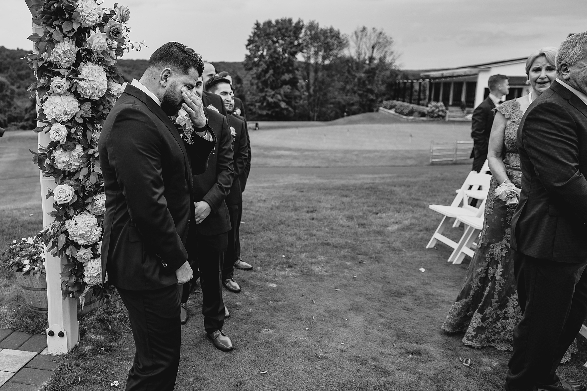 groom wipes away tears during ceremony on lawn at Skyview Golf Club