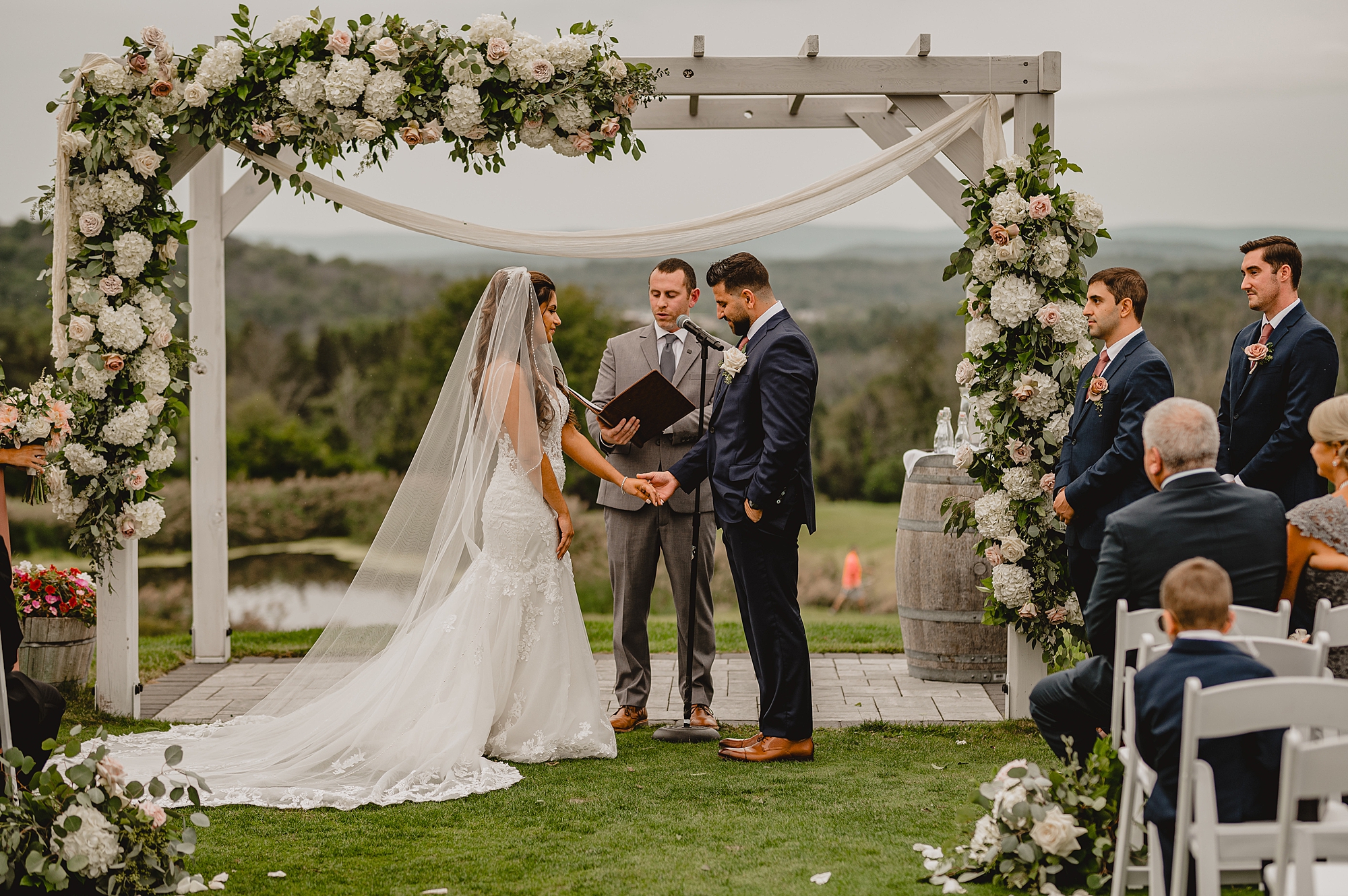 bride and groom hold hands during ceremony on lawn at Skyview Golf Club