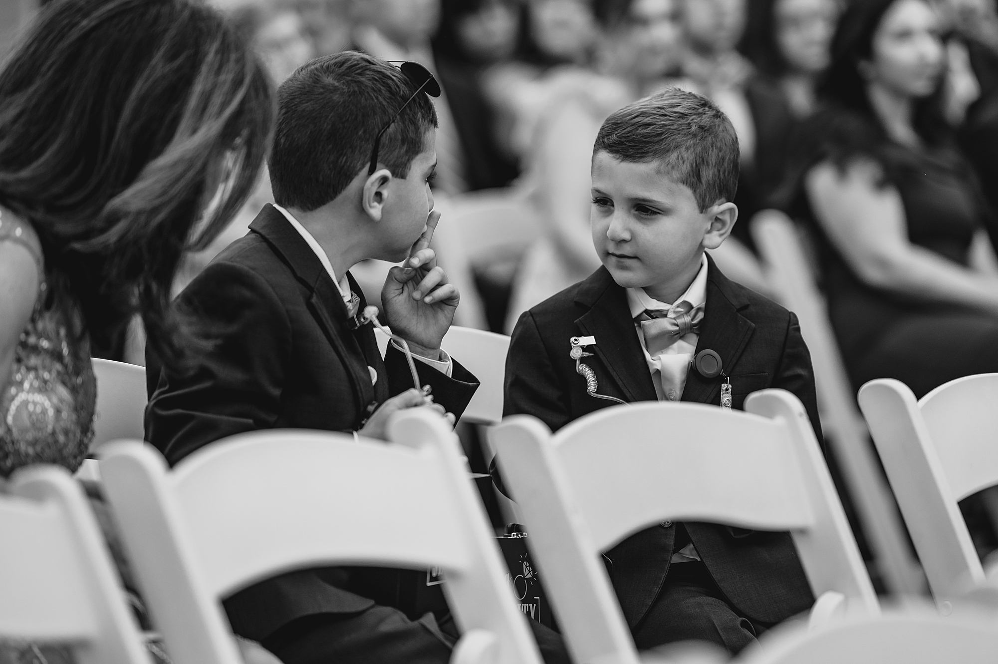 ring bearers laugh sitting together on white chairs