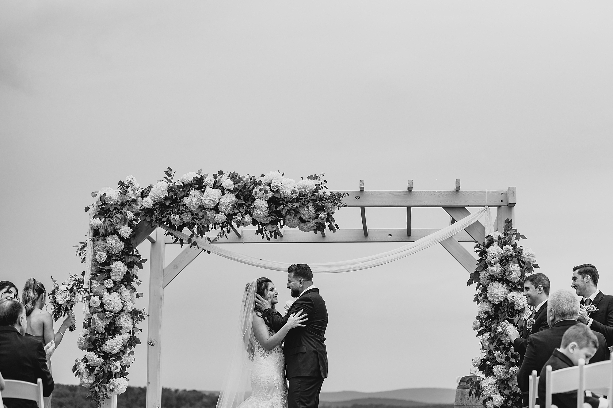 groom holds bride's cheek during ceremony on lawn at Skyview Golf Club