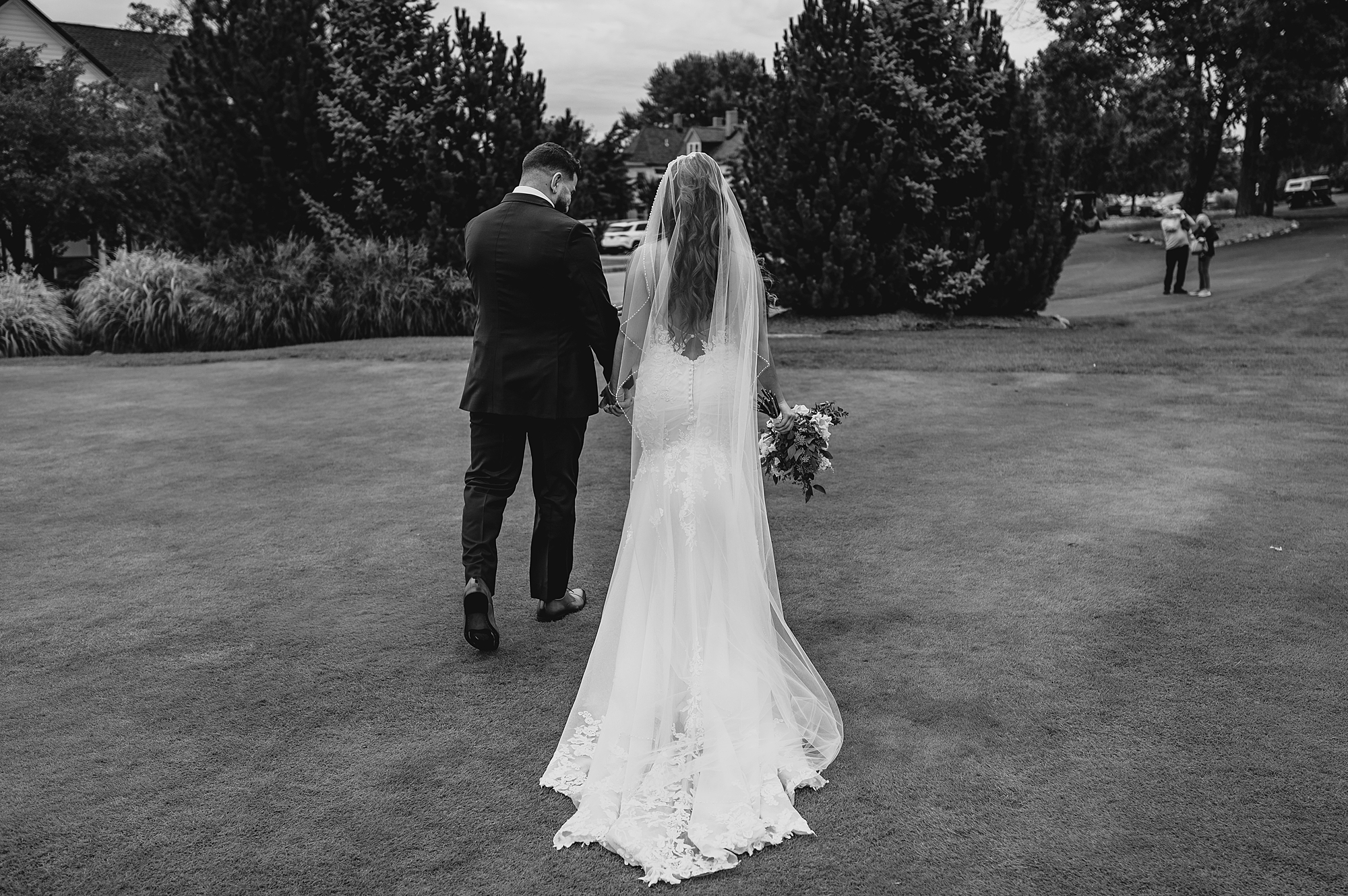 bride and groom walk across lawn after ceremony at Skyview Golf Club
