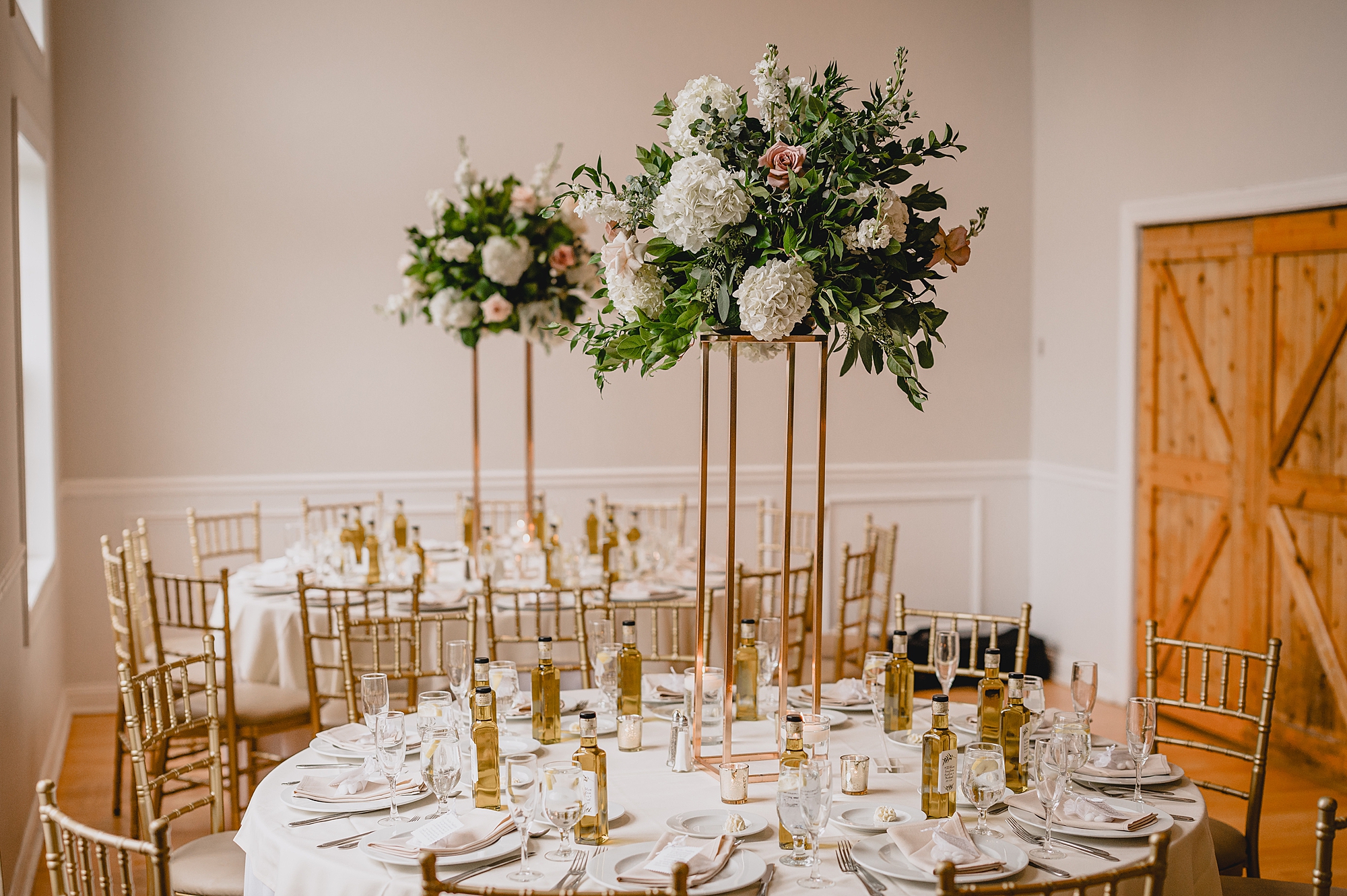 wedding reception with flower centerpieces with gold vases