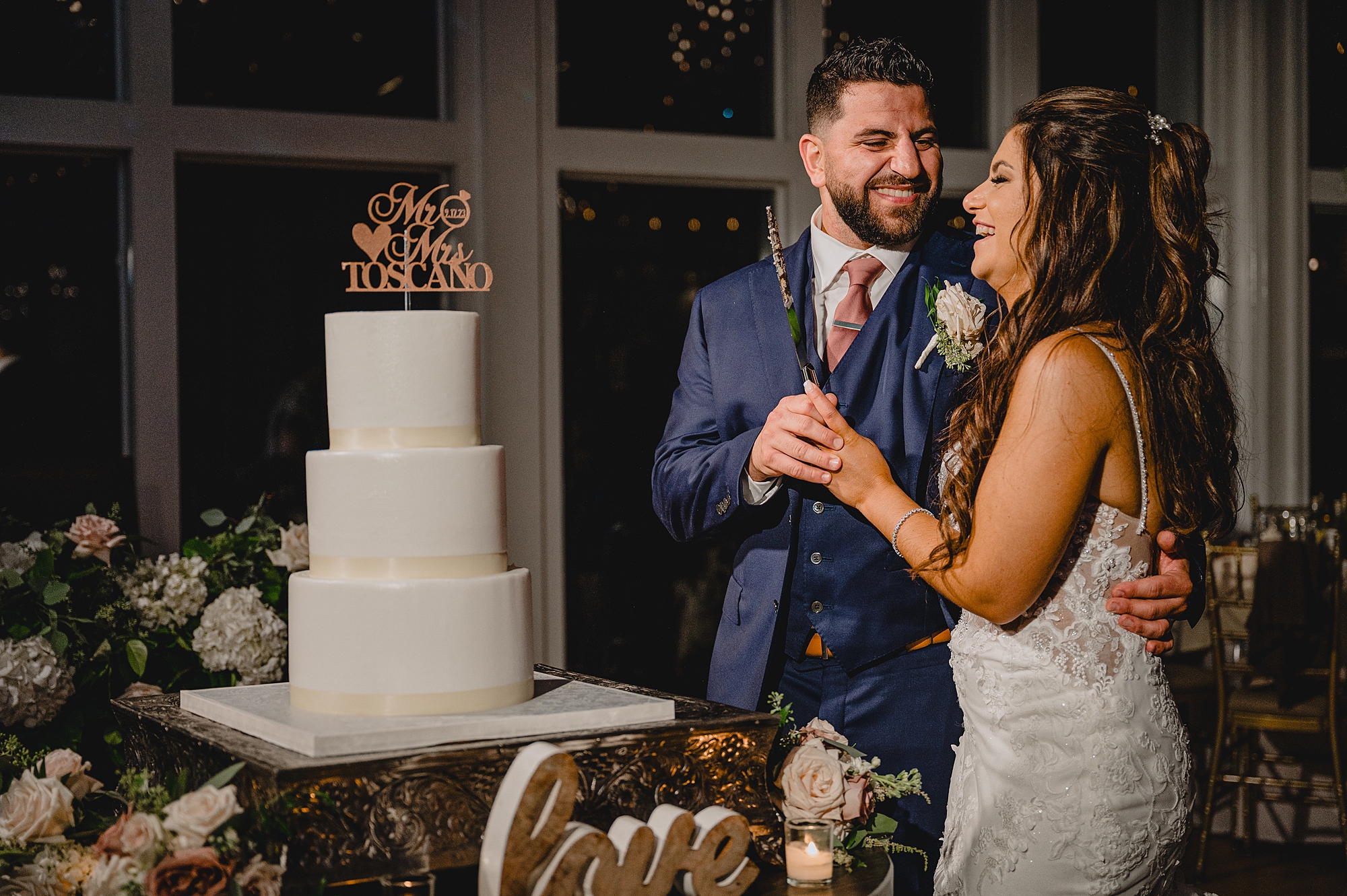 newlyweds laugh by tiered wedding cake