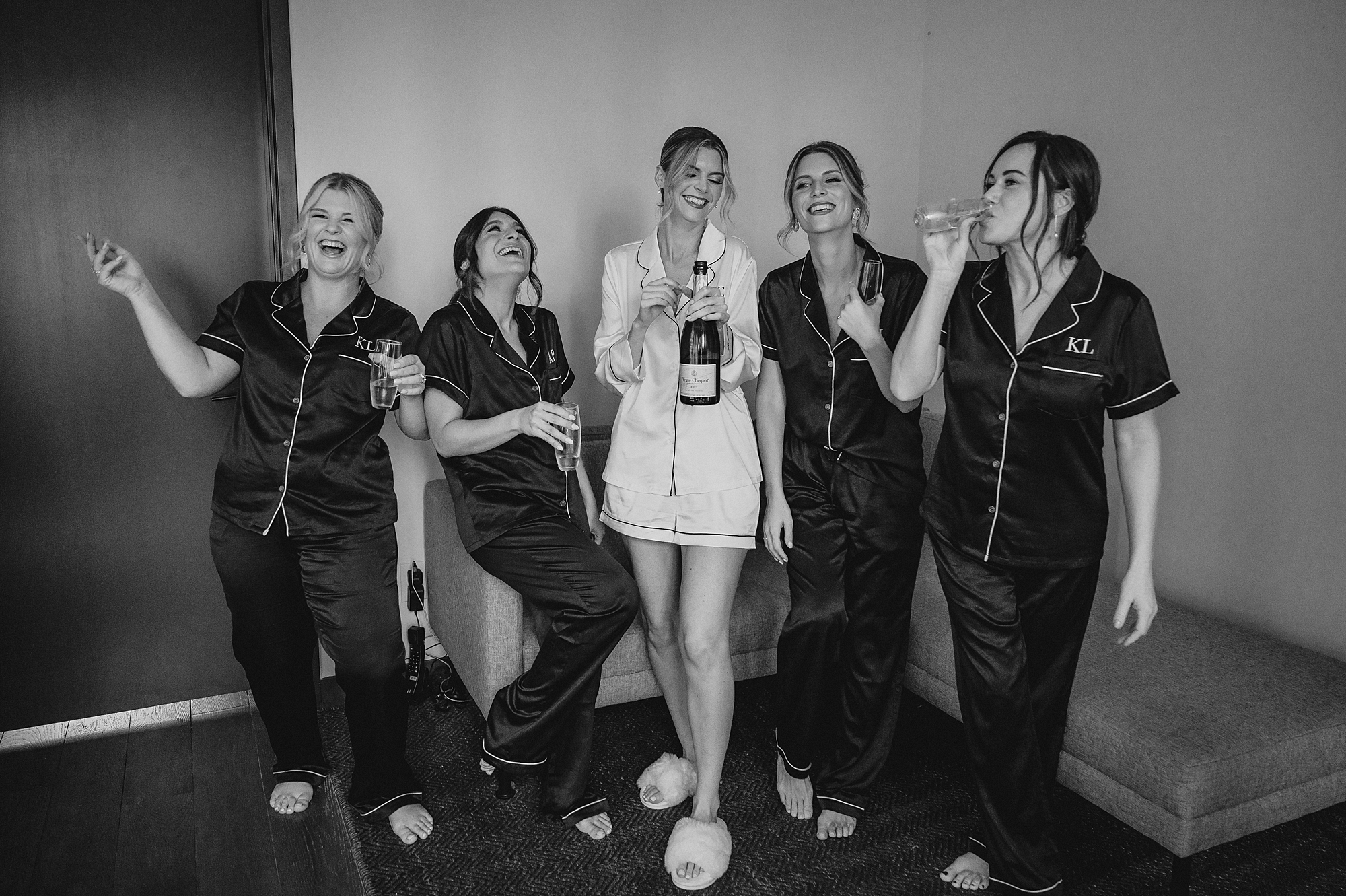 bride pops champagne with bridesmaids in Jersey City hotel room
