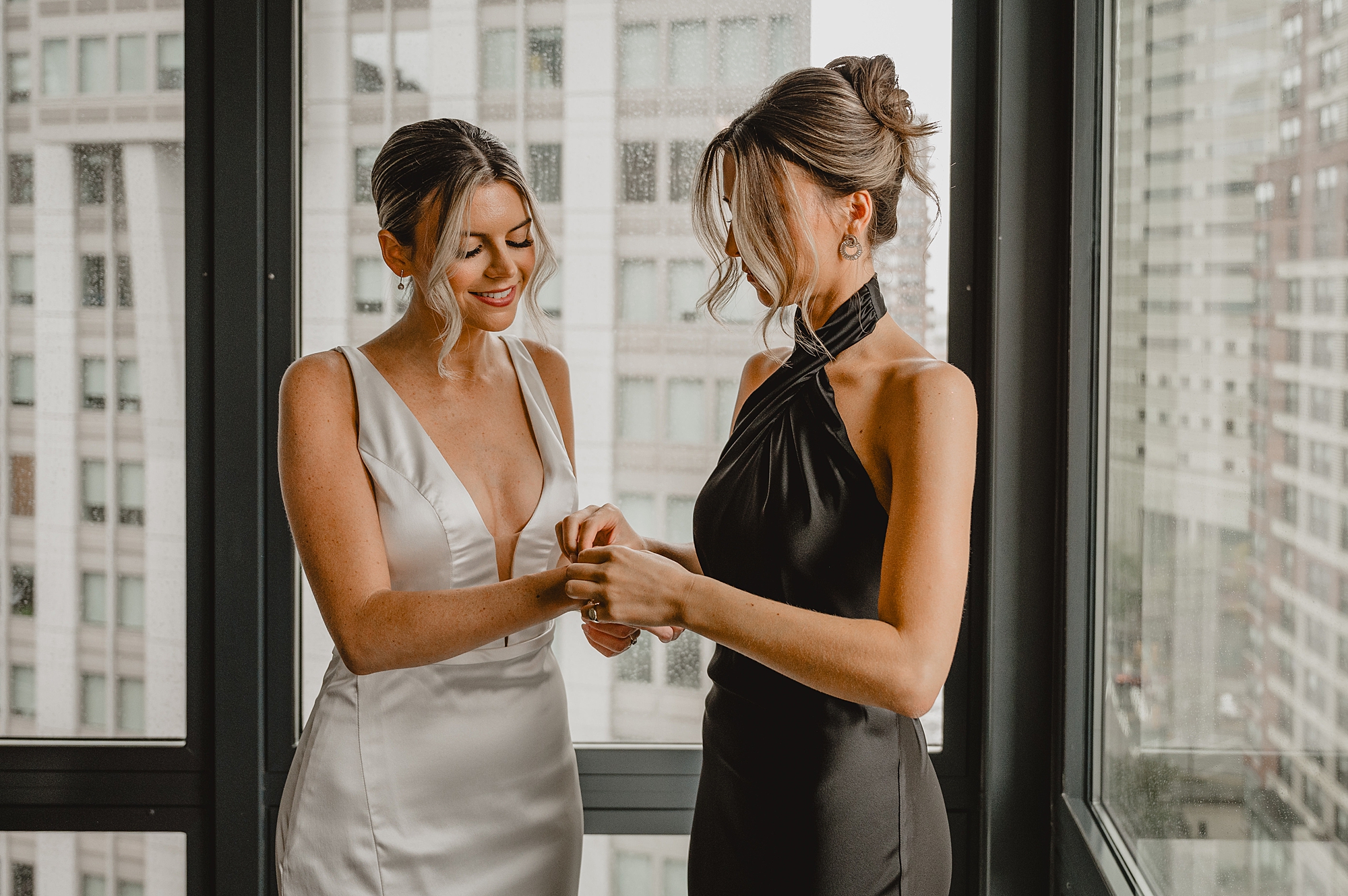 bridesmaid helps bride with bracelet on wedding day in Jersey City