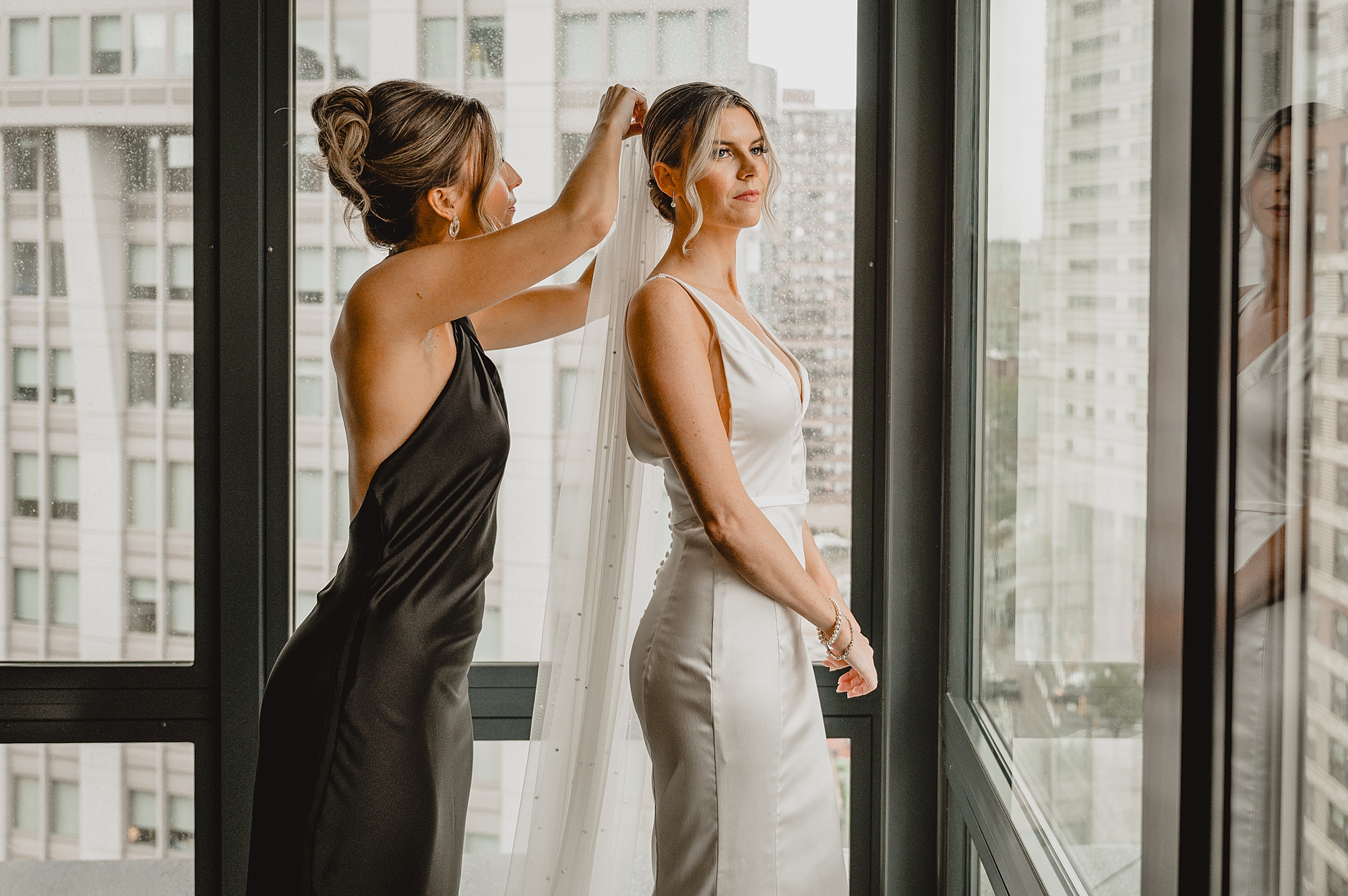 bridesmaid helps place veil for bride during prep in Jersey City hotel