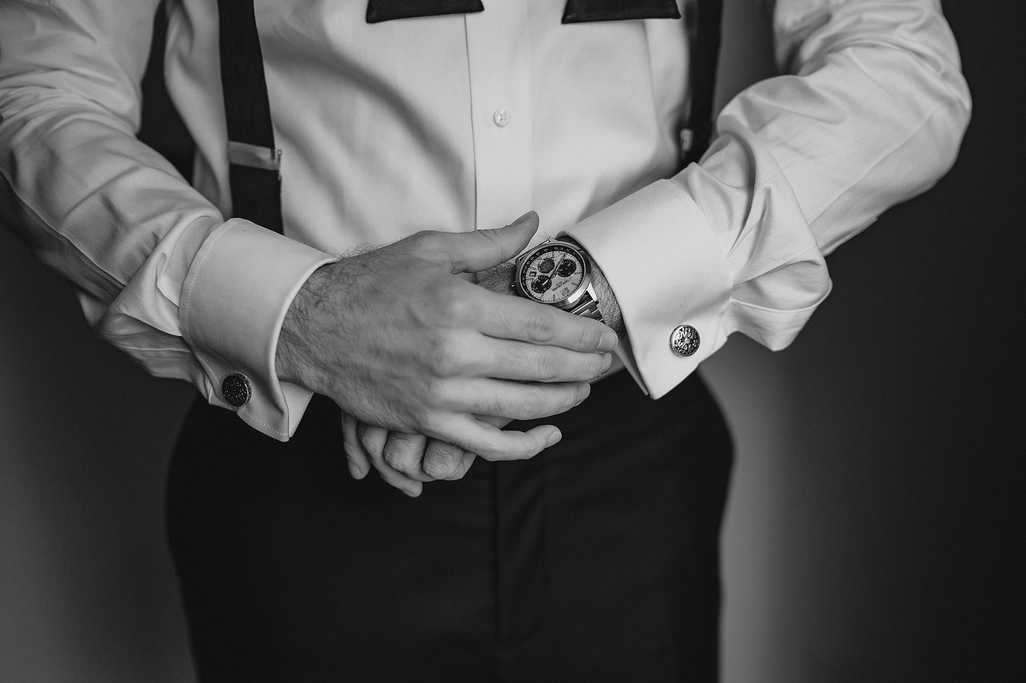man adjusts watch on wrist for wedding day in Jersey City