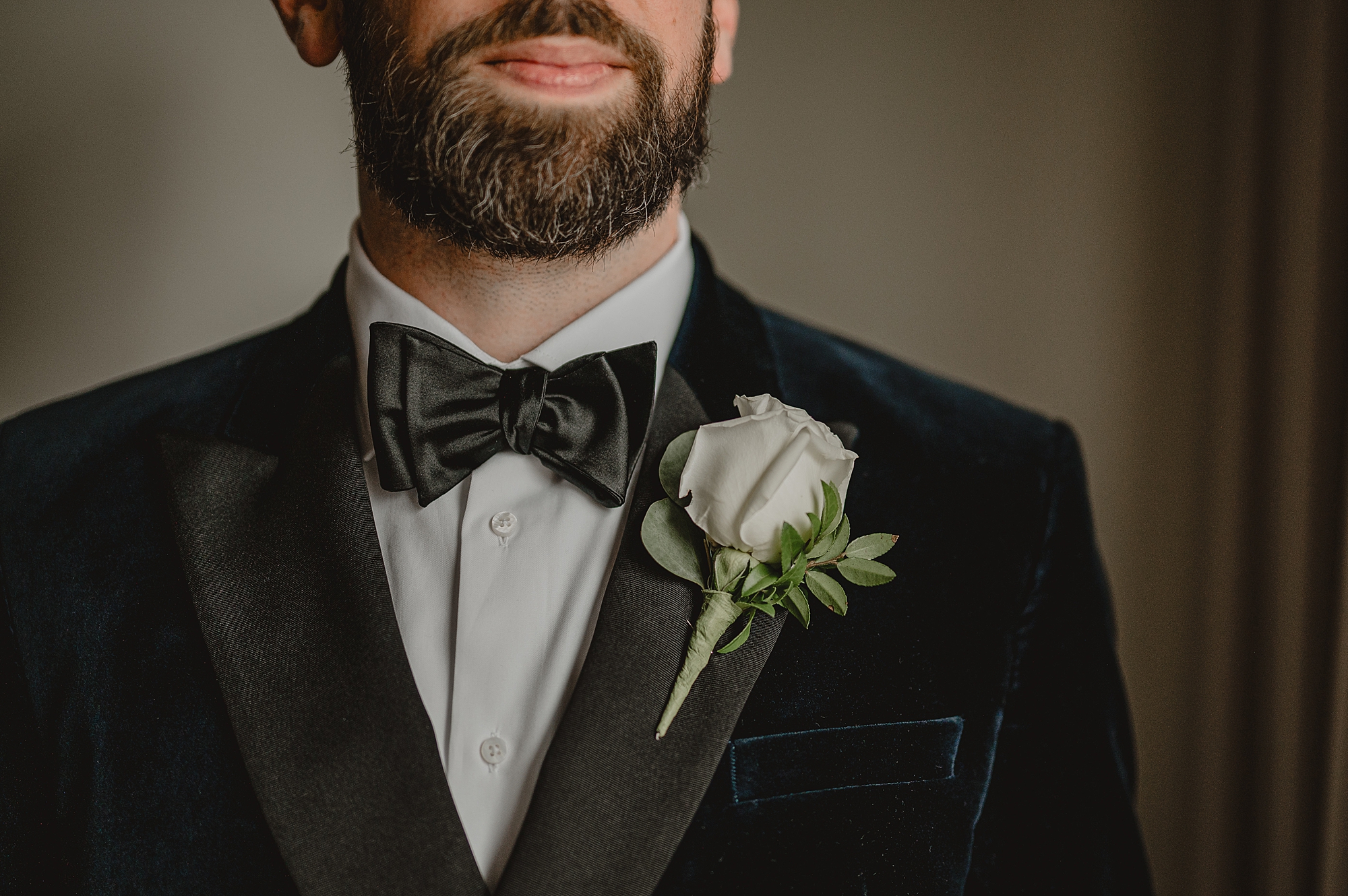 groom's white rose boutonnière on lapel of velvet jacket