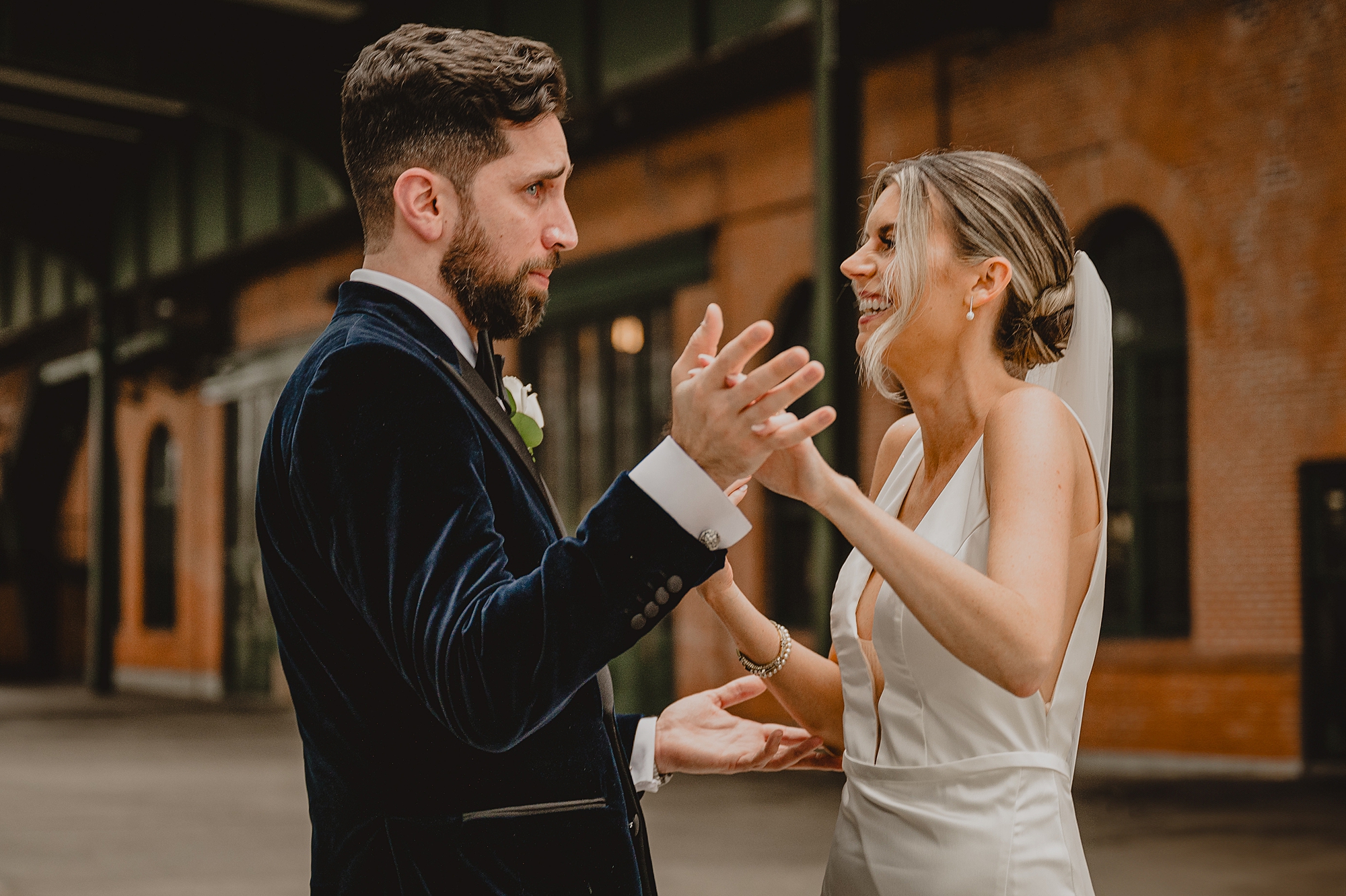 bride and groom hold hands smiling and talking