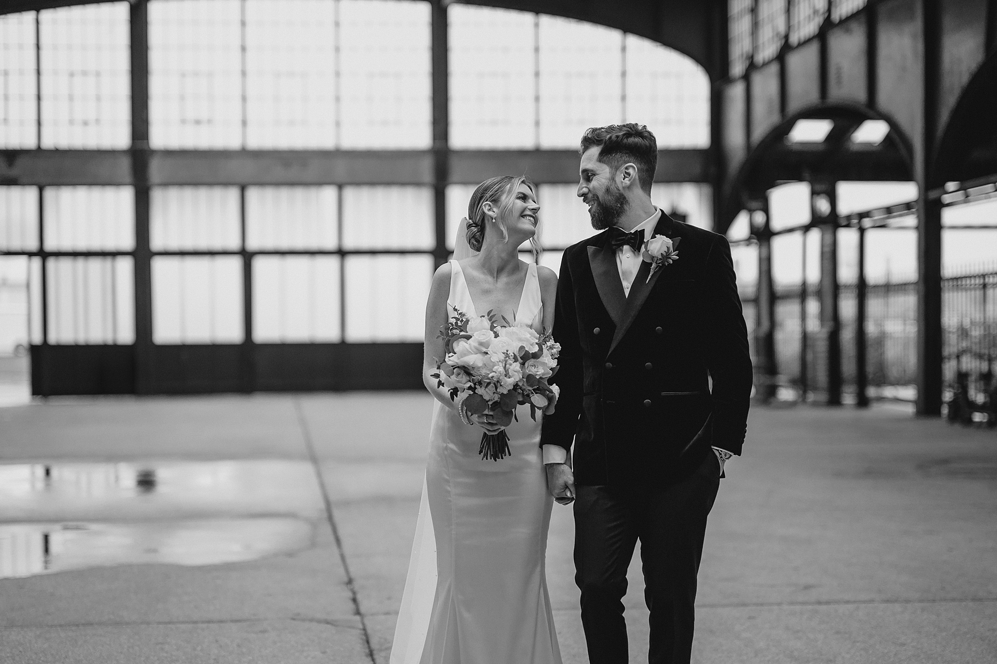 bride smiles at groom holding large bouquet in front of her