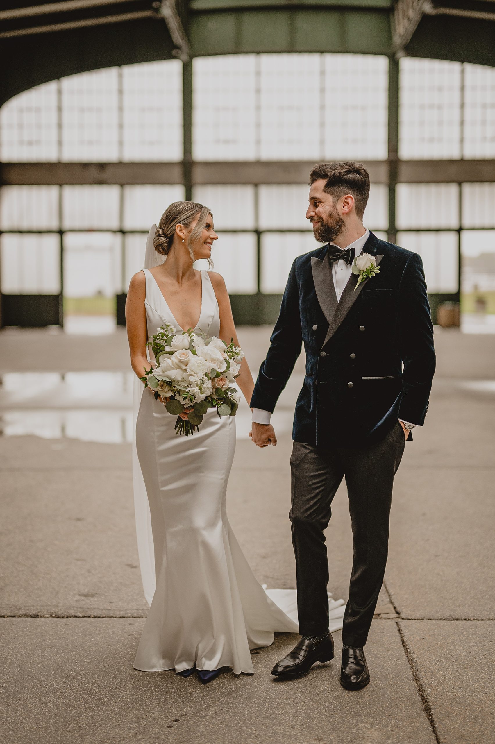 bride and groom hold hands walking inside Maritime Parc