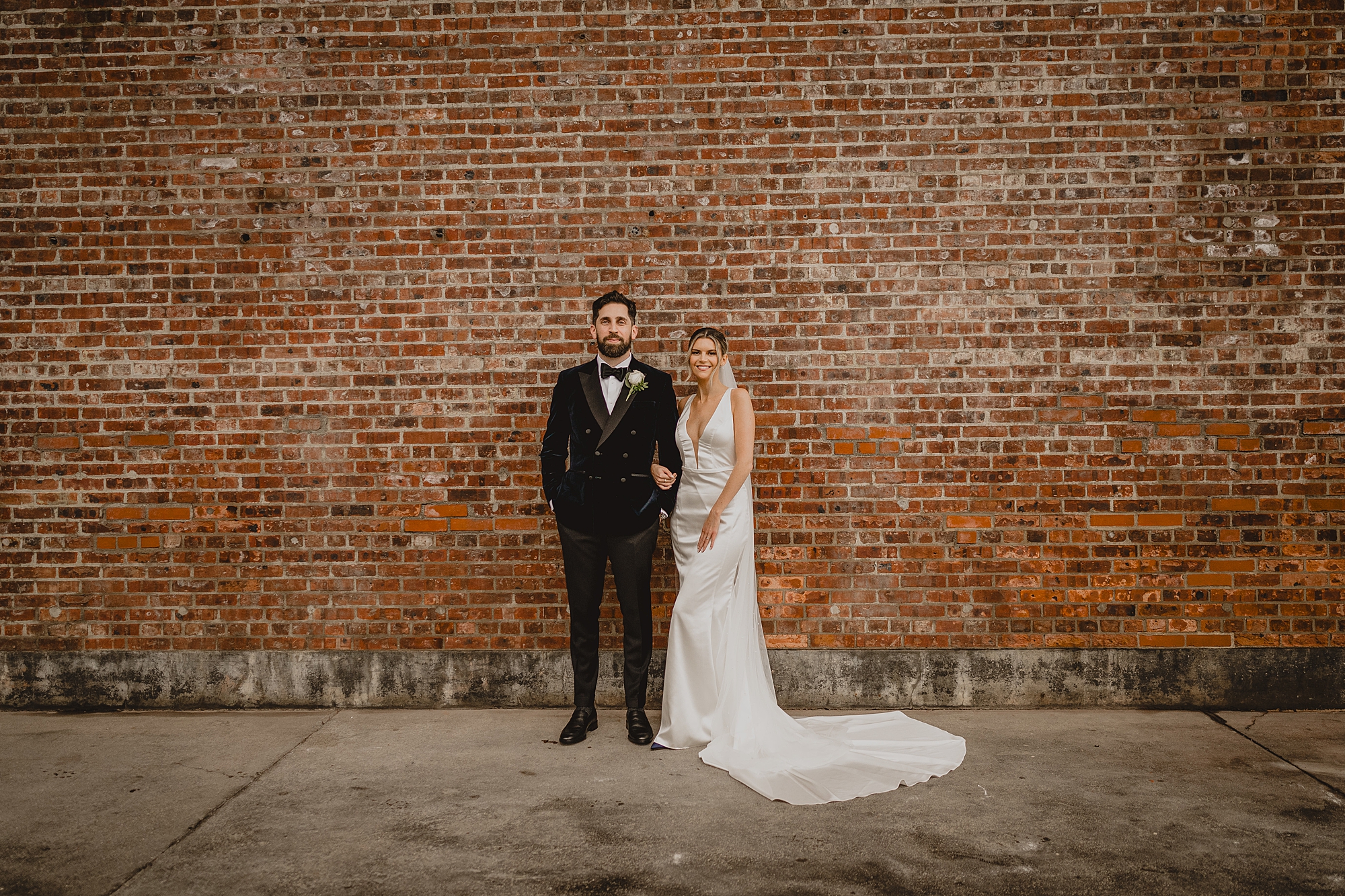 bride and groom hold hands standing in front of brick wall at Maritime Parc