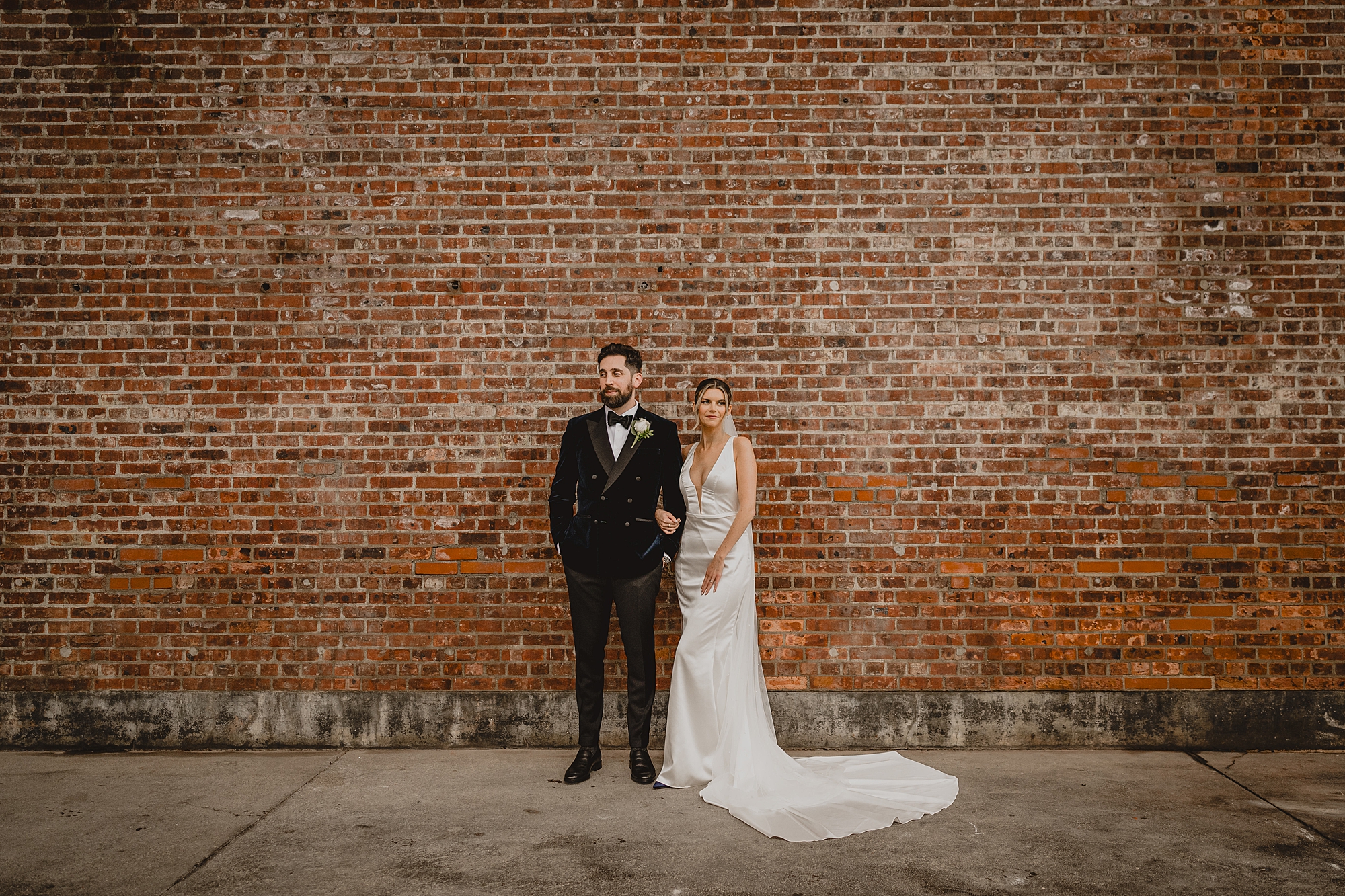 bride and groom hold hands standing in front of brick wall at Maritime Parc